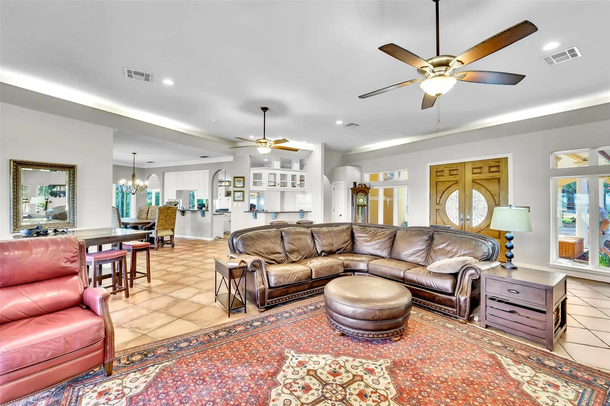 Living room with a ceiling fan, light tile patterned floors, arched walkways, a chandelier, and recessed lighting