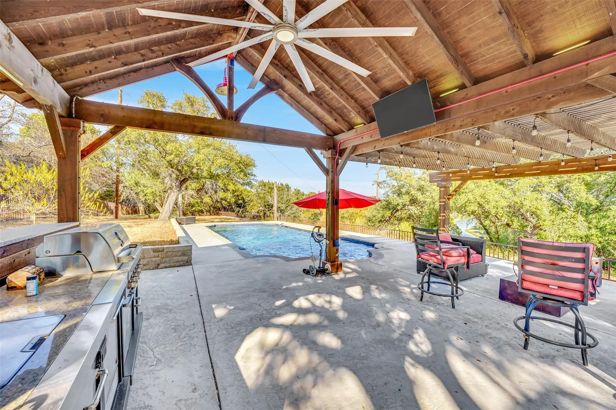 View of patio featuring a ceiling fan, an outdoor kitchen, a gazebo, and an outdoor pool