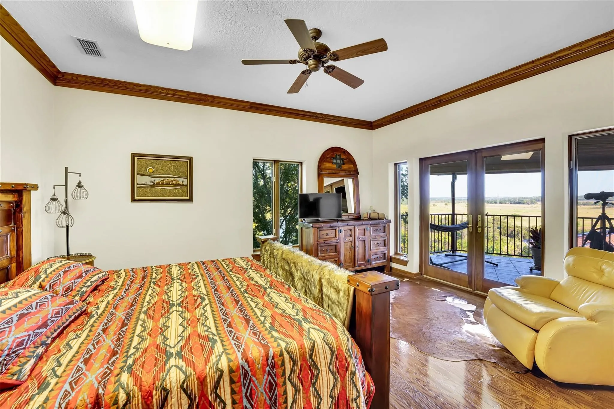 Bedroom featuring french doors, ornamental molding, wood finished floors, multiple windows, and access to outside