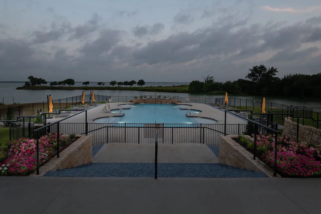 Multi-level swimming pool with integrated seating surrounded by a black metal fence