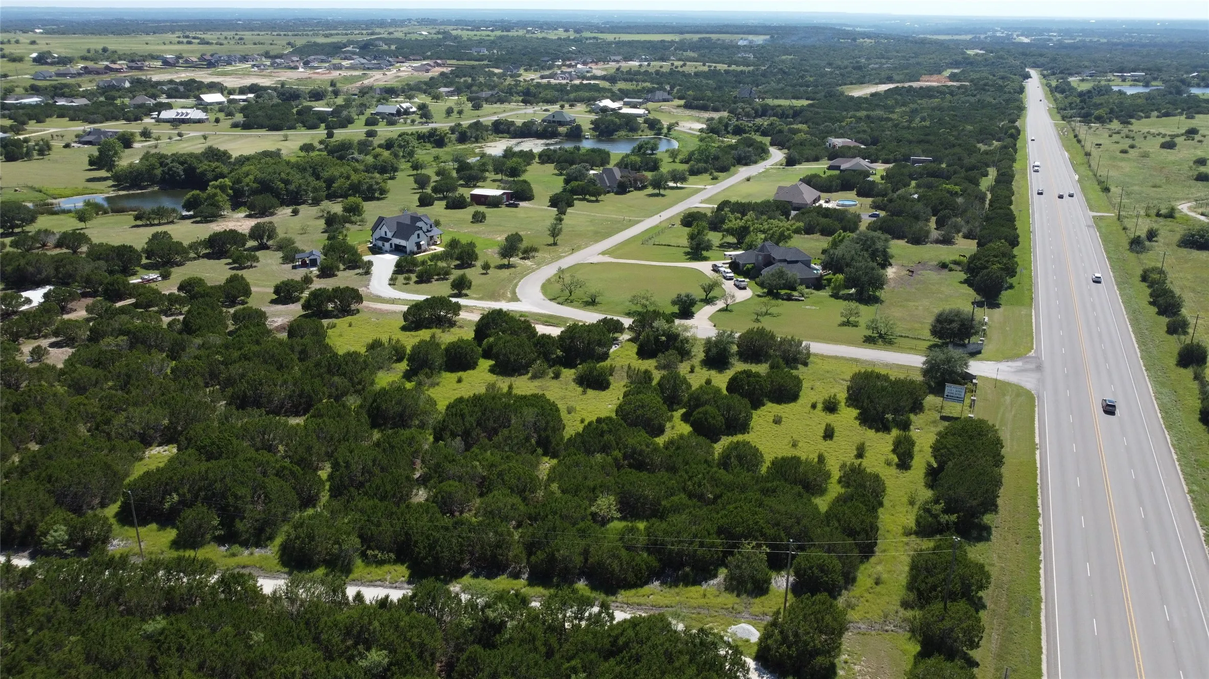 Aerial view of property and surrounding area featuring a nearby body of water and a main thoroughfare