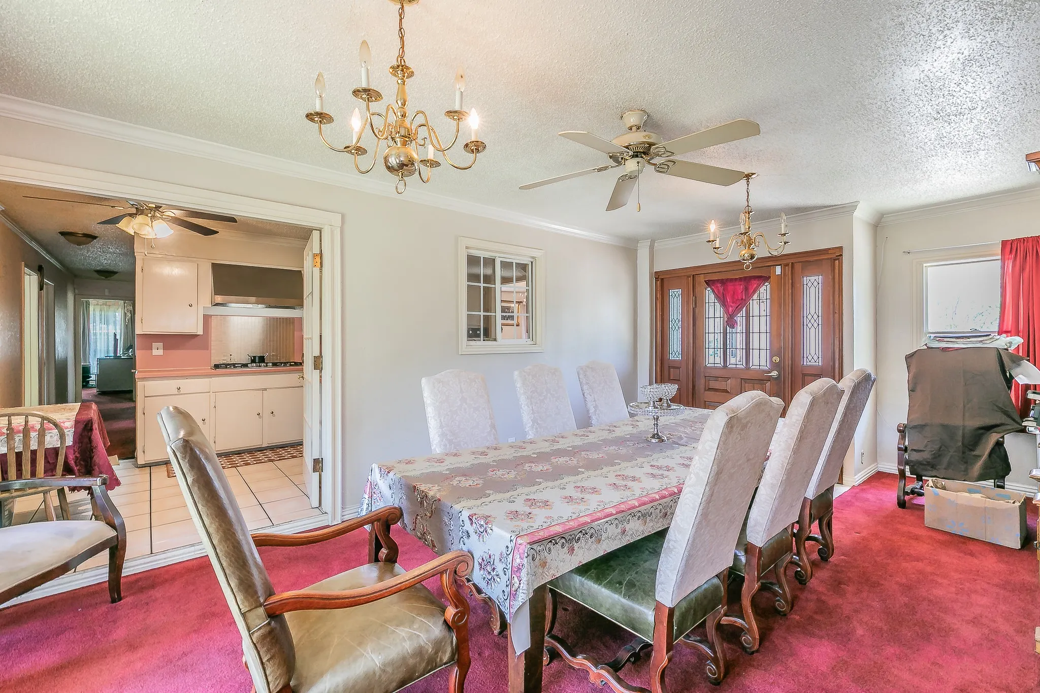 Carpeted dining area featuring ceiling fan, crown molding, a textured ceiling, and a chandelier