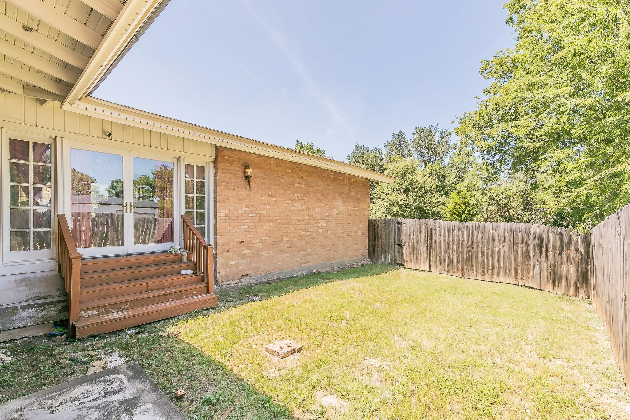 Fenced backyard with entry steps and french doors