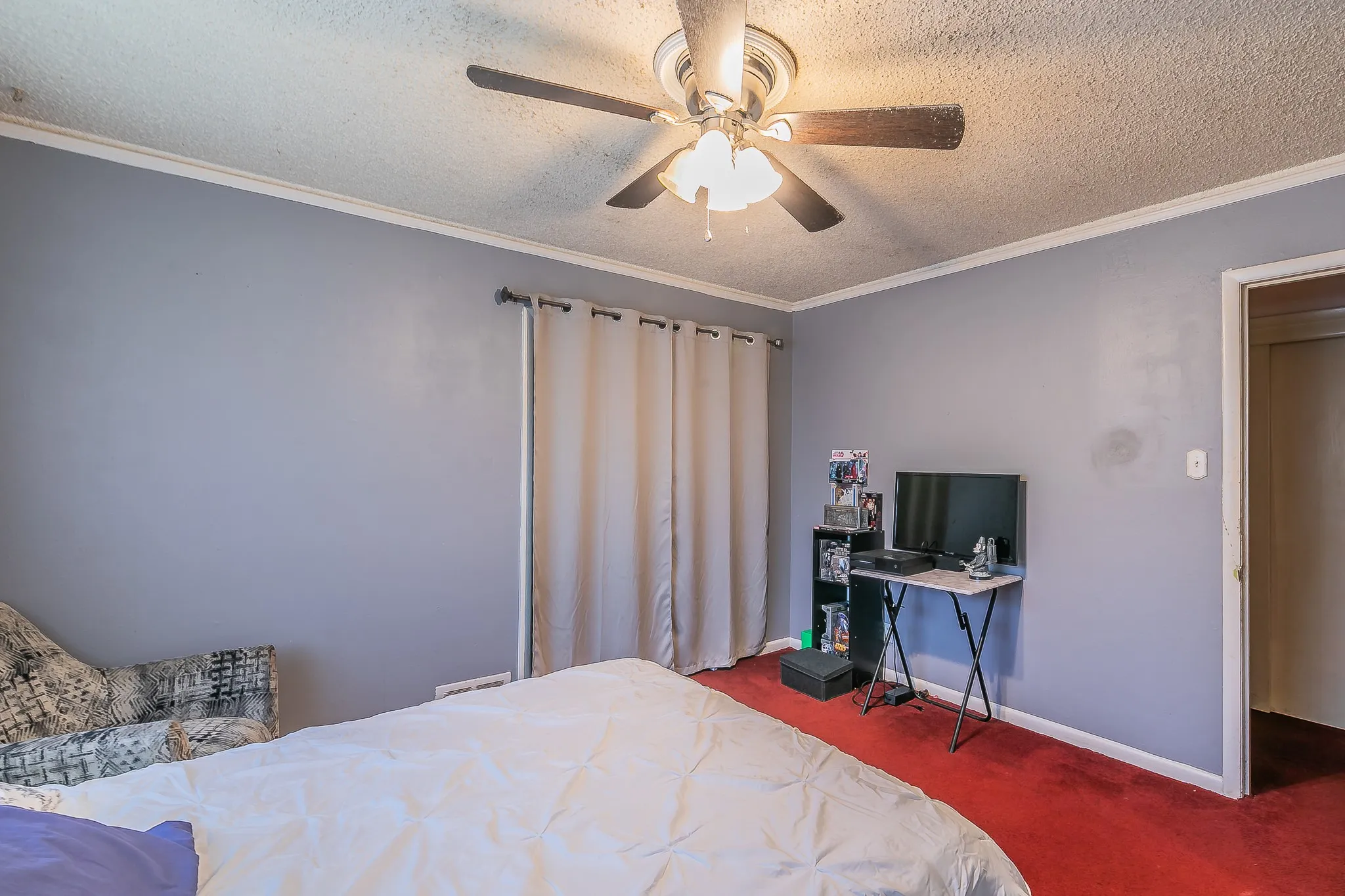 Bedroom featuring a textured ceiling, carpet flooring, a ceiling fan, and ornamental molding