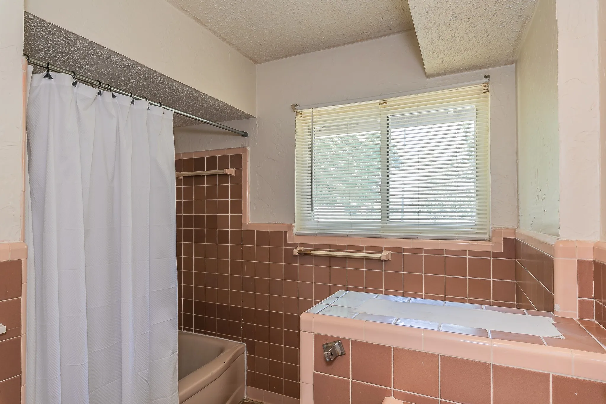 Full bath with tile walls, a textured ceiling, wainscoting, and shower / bath combination with curtain