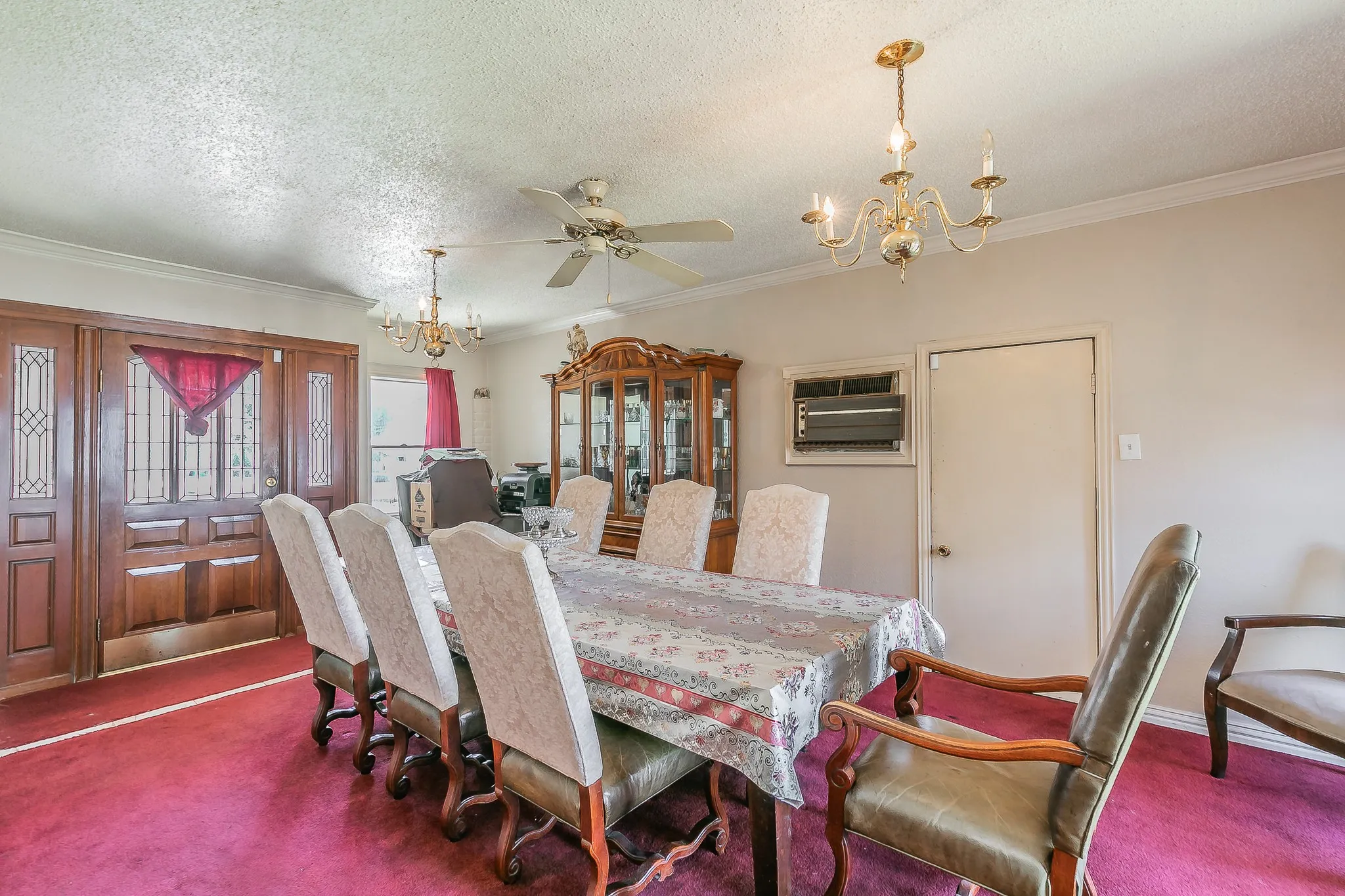Dining room featuring a chandelier, dark colored carpet, crown molding, a ceiling fan, and a textured ceiling