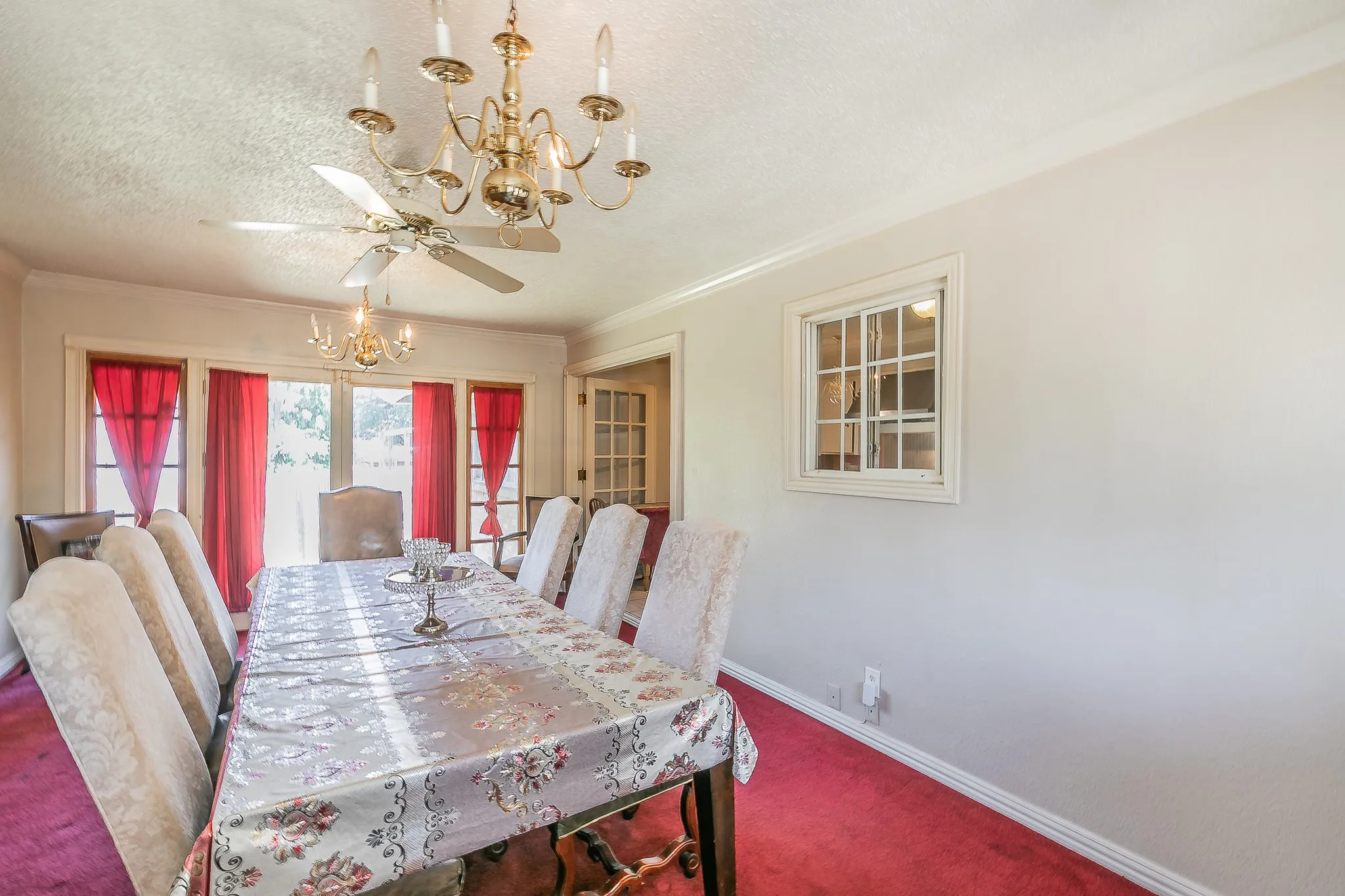 Carpeted dining space featuring a chandelier, crown molding, a ceiling fan, and a textured ceiling