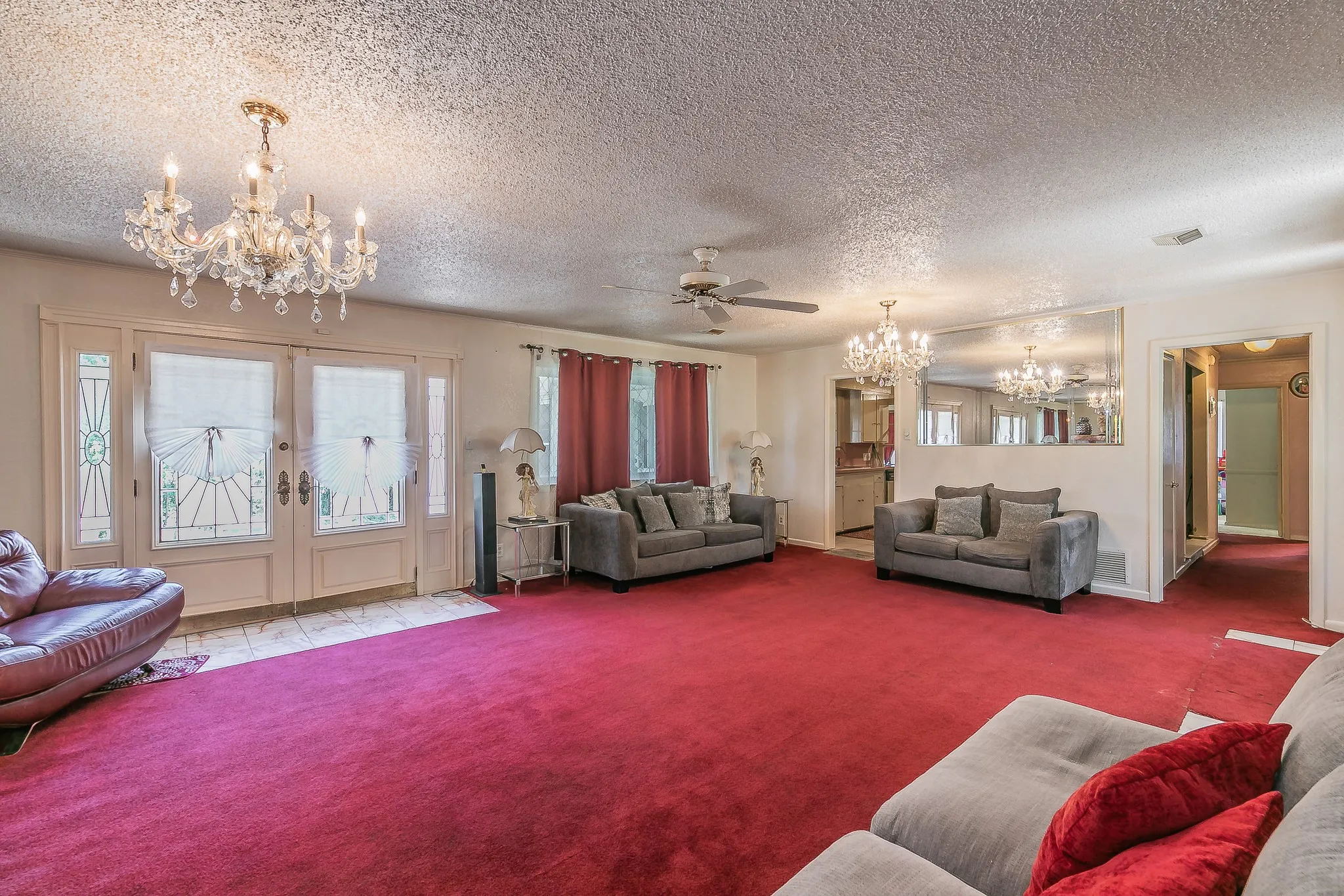 Carpeted living area featuring a chandelier, a textured ceiling, french doors, plenty of natural light, and ceiling fan