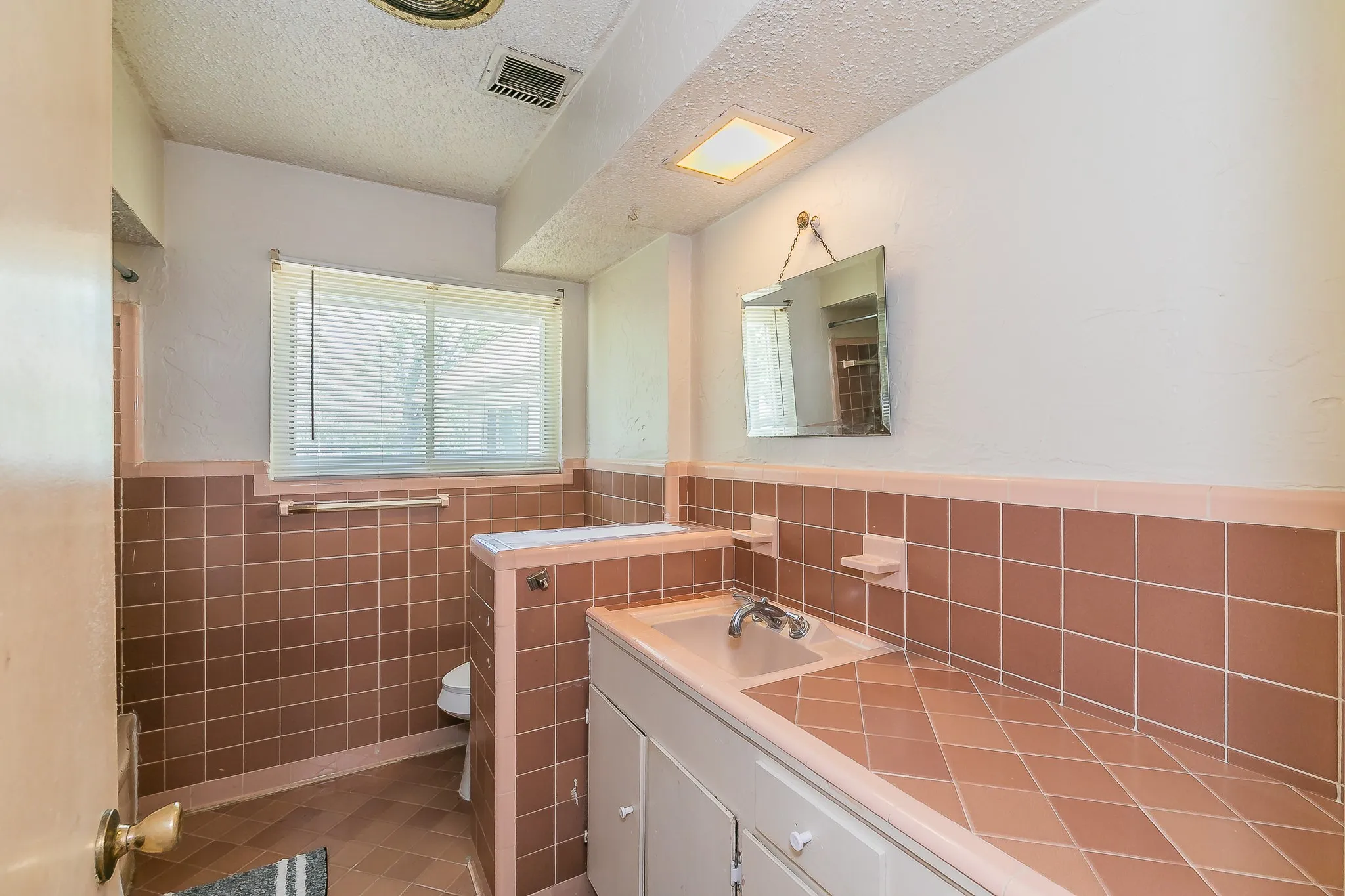 Bathroom with tile walls, vanity, wainscoting, a textured ceiling, and tile patterned floors