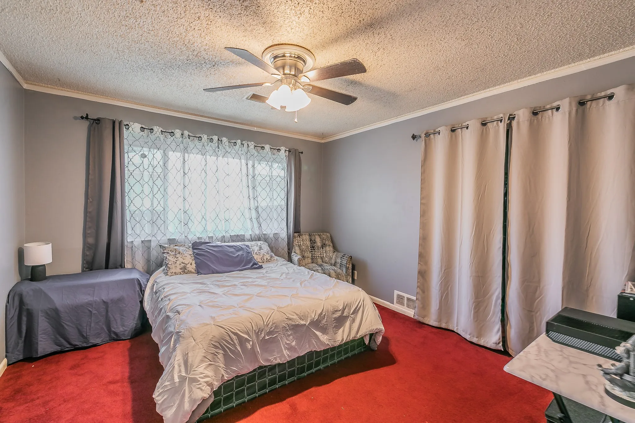 Bedroom with carpet flooring, a textured ceiling, crown molding, and a ceiling fan