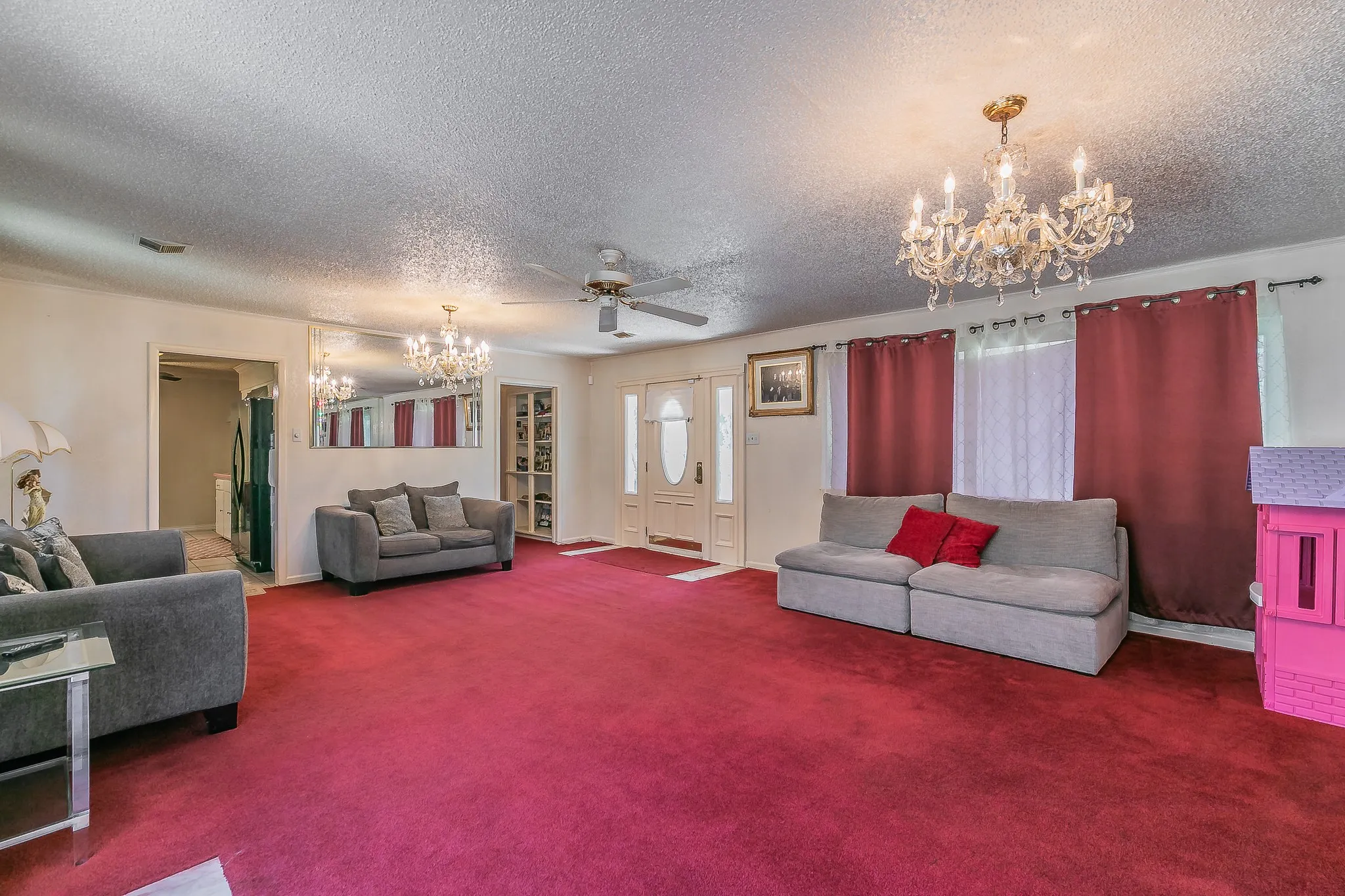 Living room with a chandelier, a textured ceiling, carpet, and a ceiling fan