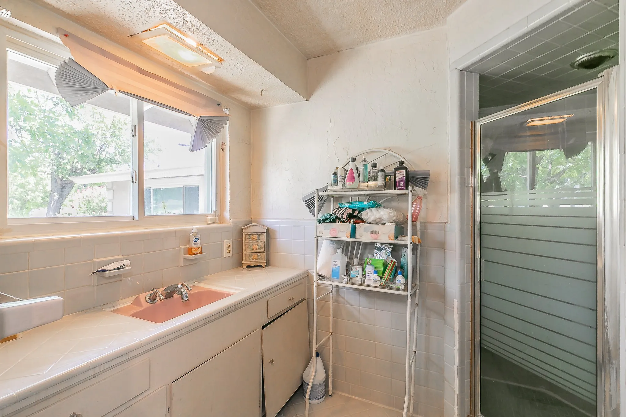 Bathroom with vanity, plenty of natural light, a textured ceiling, a shower stall, and tile walls