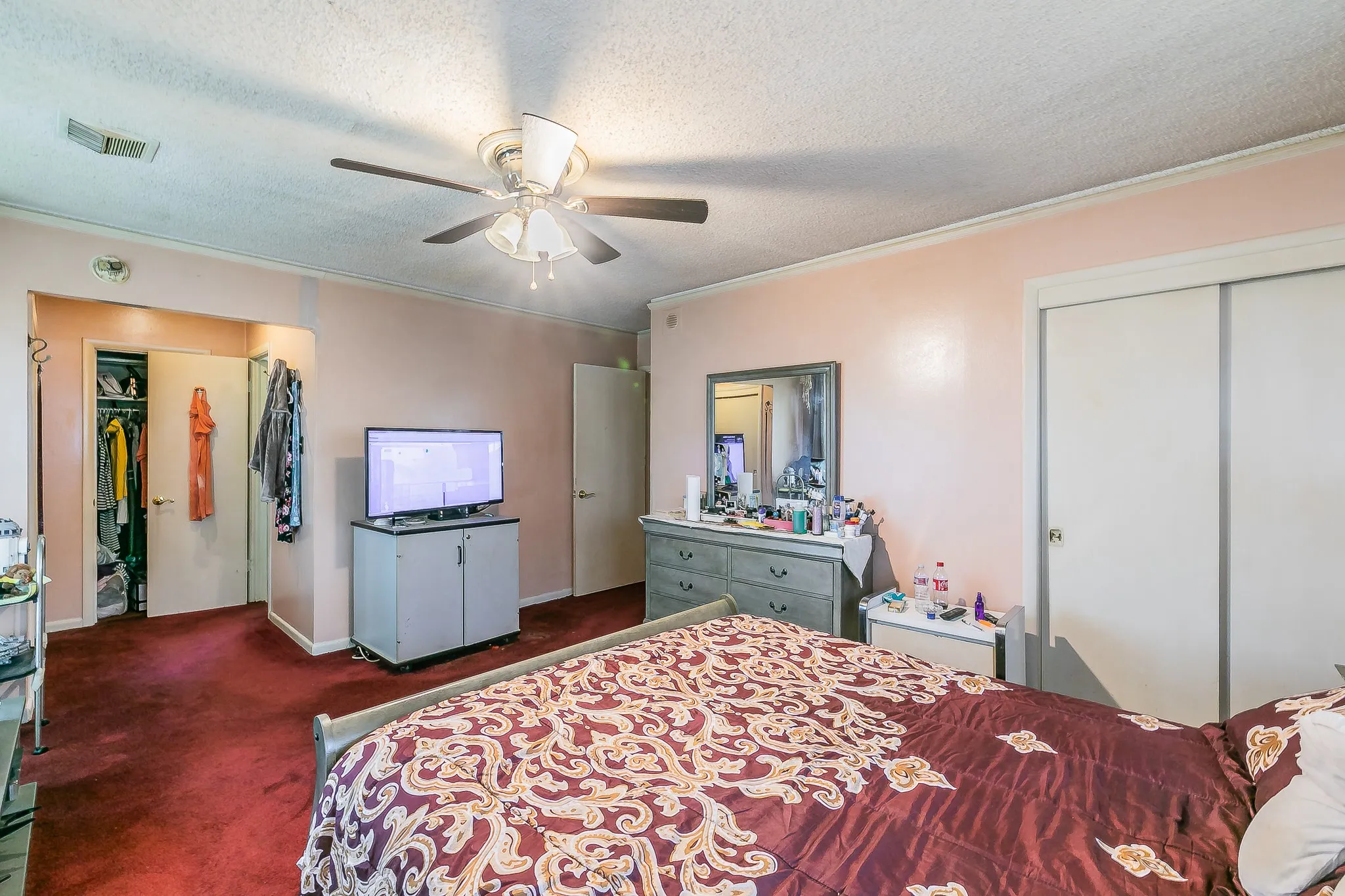 Carpeted bedroom with a textured ceiling, ornamental molding, and ceiling fan