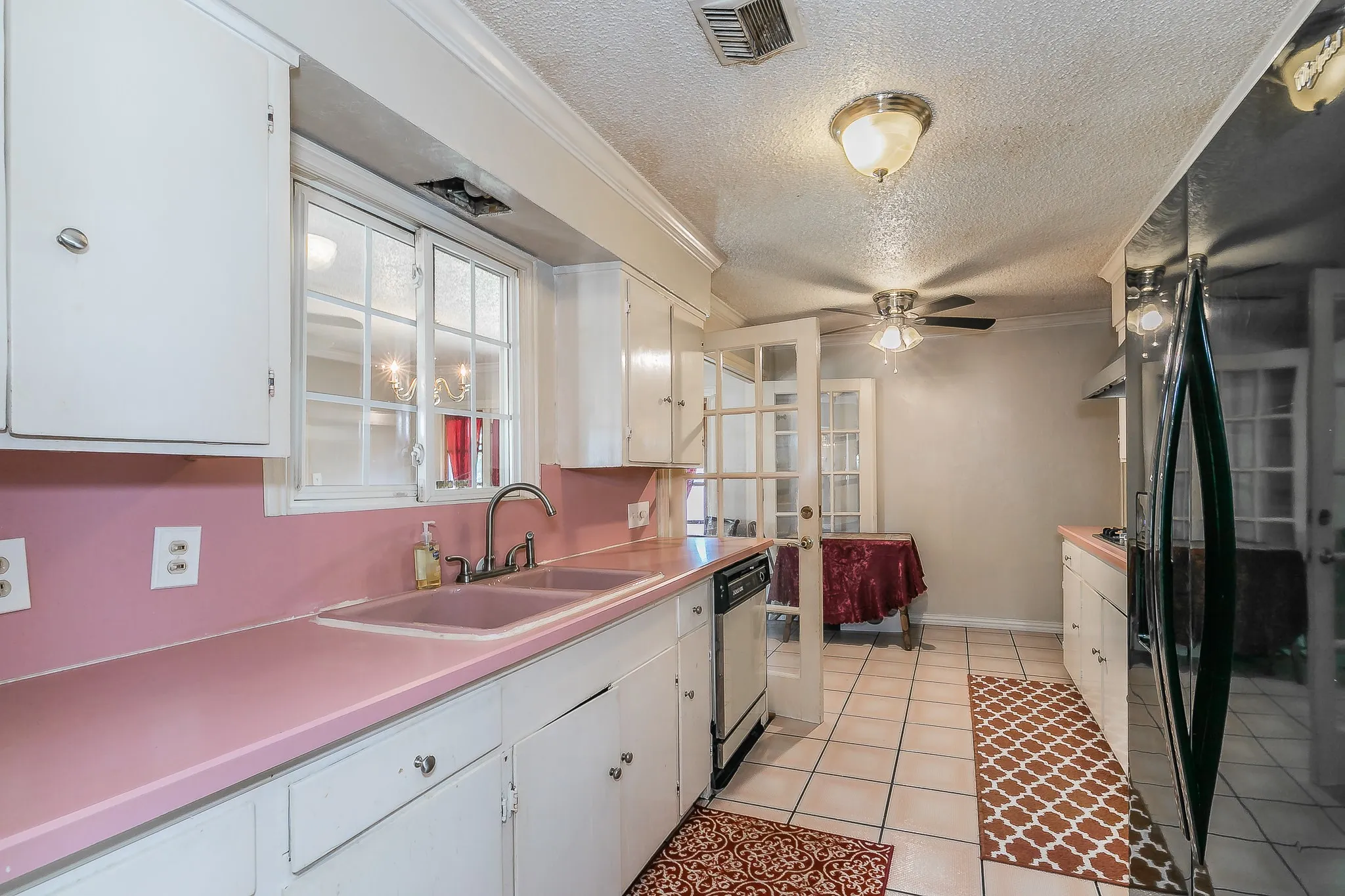 Kitchen with freestanding refrigerator, a textured ceiling, white cabinetry, a ceiling fan, and light tile patterned floors