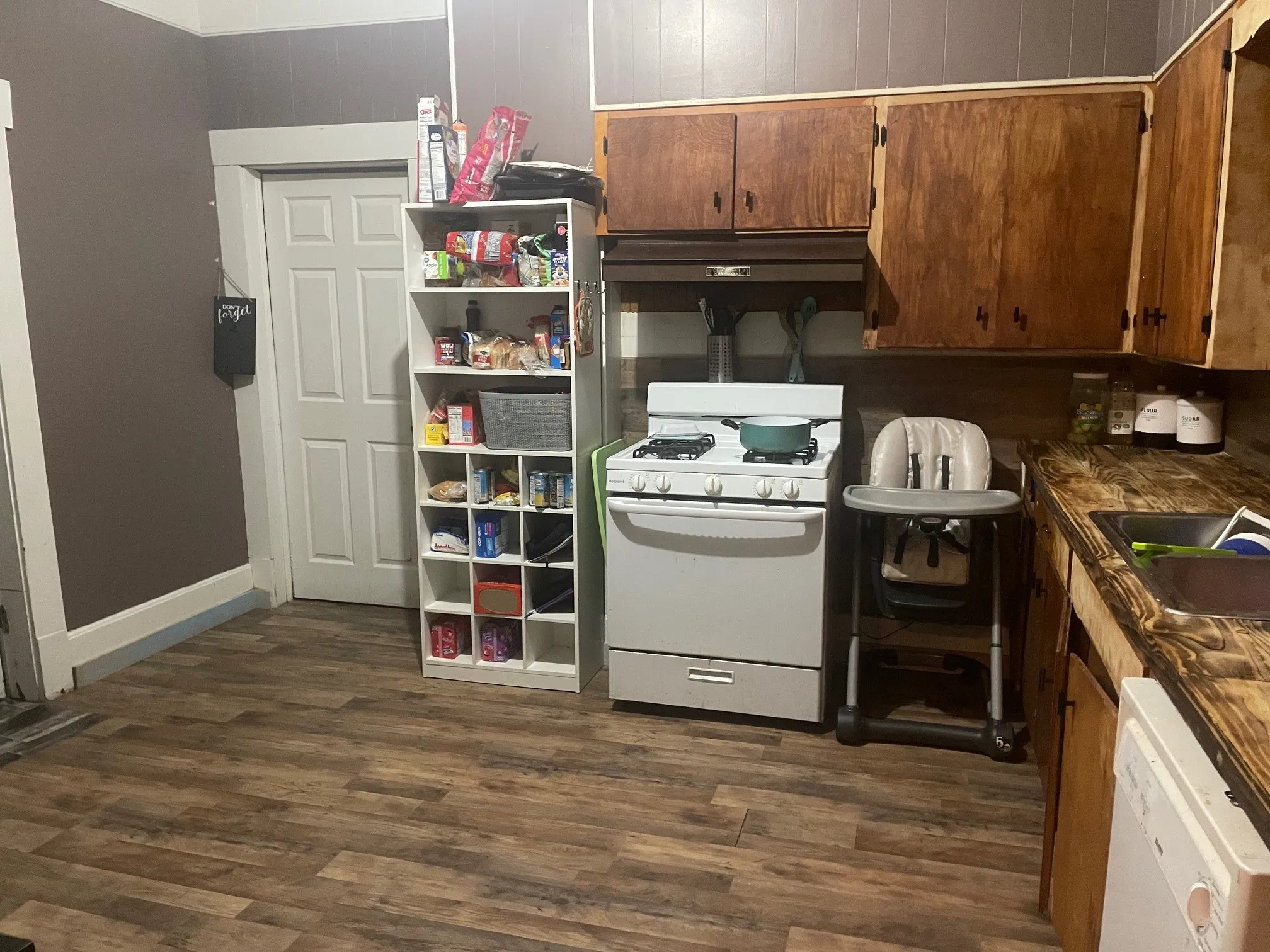 Kitchen with white appliances, dark wood-style flooring, extractor fan, and brown cabinets
