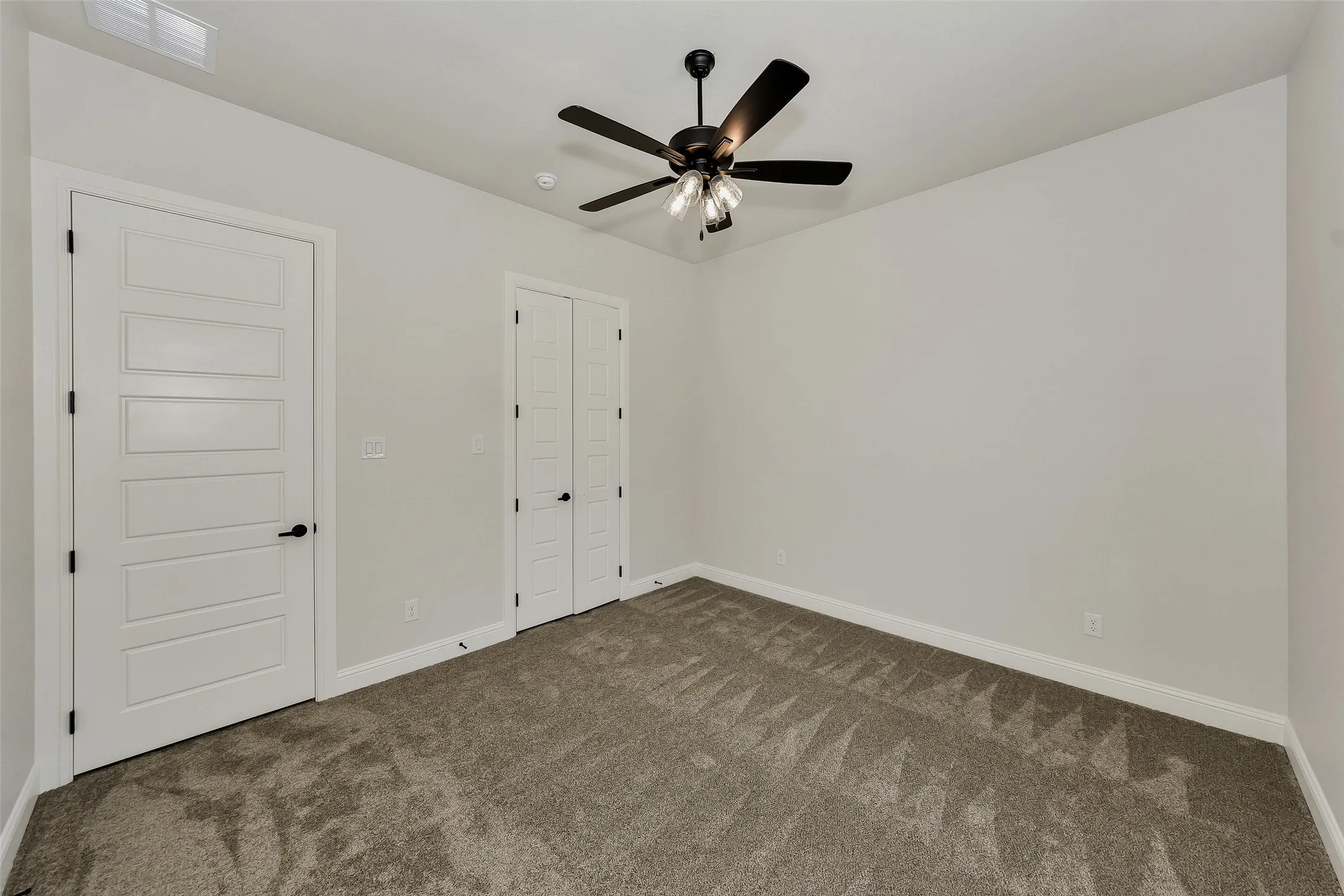 Unfurnished bedroom featuring dark carpet, a closet, and a ceiling fan