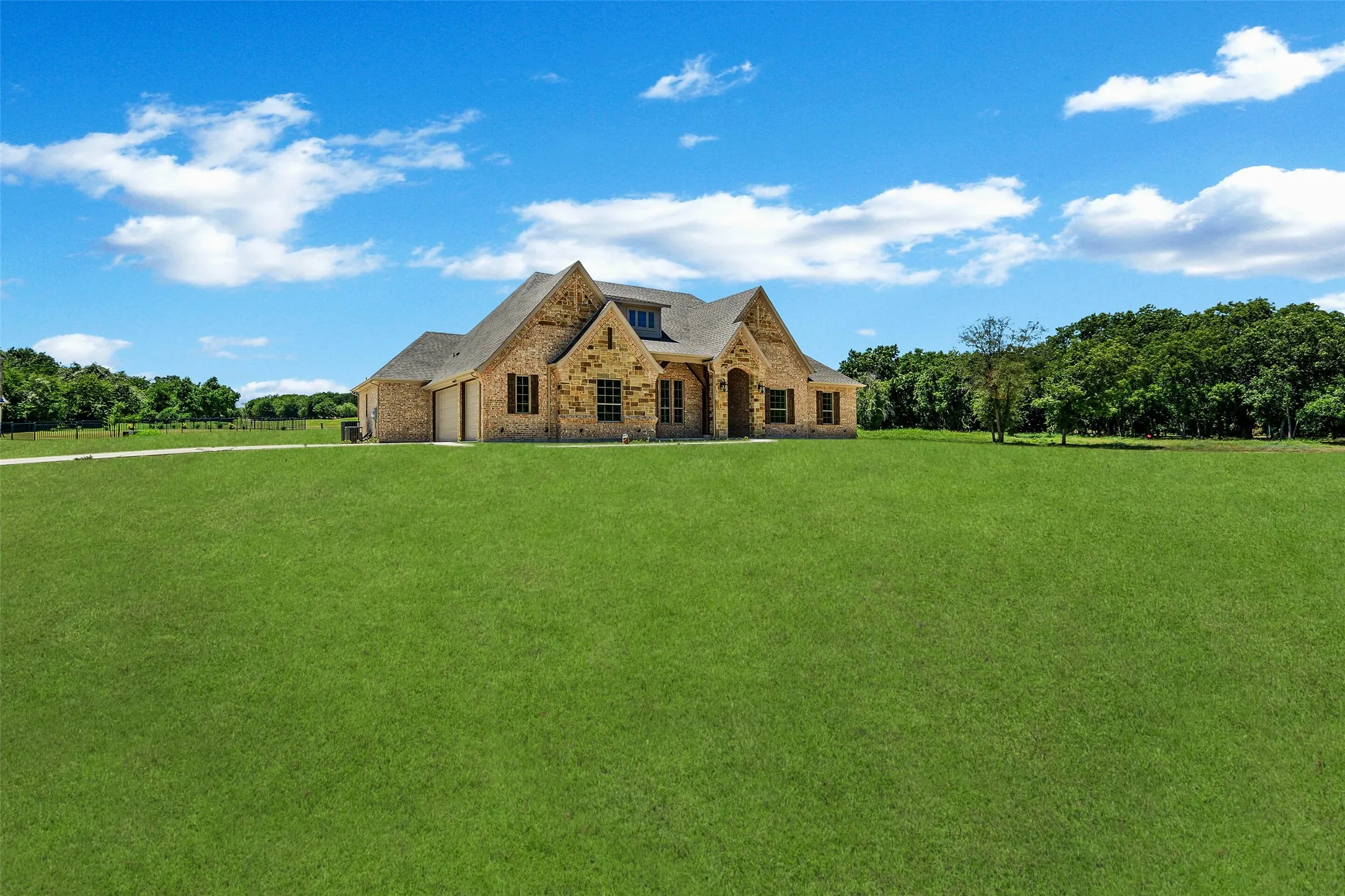 View of front of property with brick siding, stone siding, an attached garage, and a front lawn