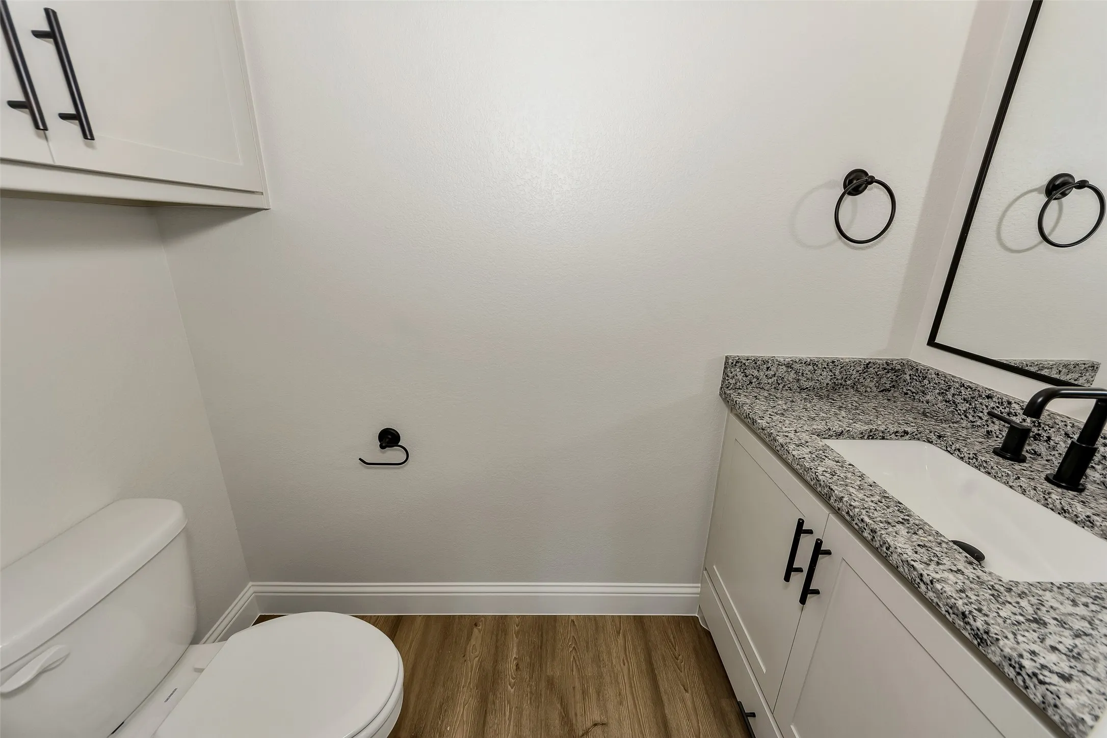 Half bathroom featuring vanity and wood finished floors