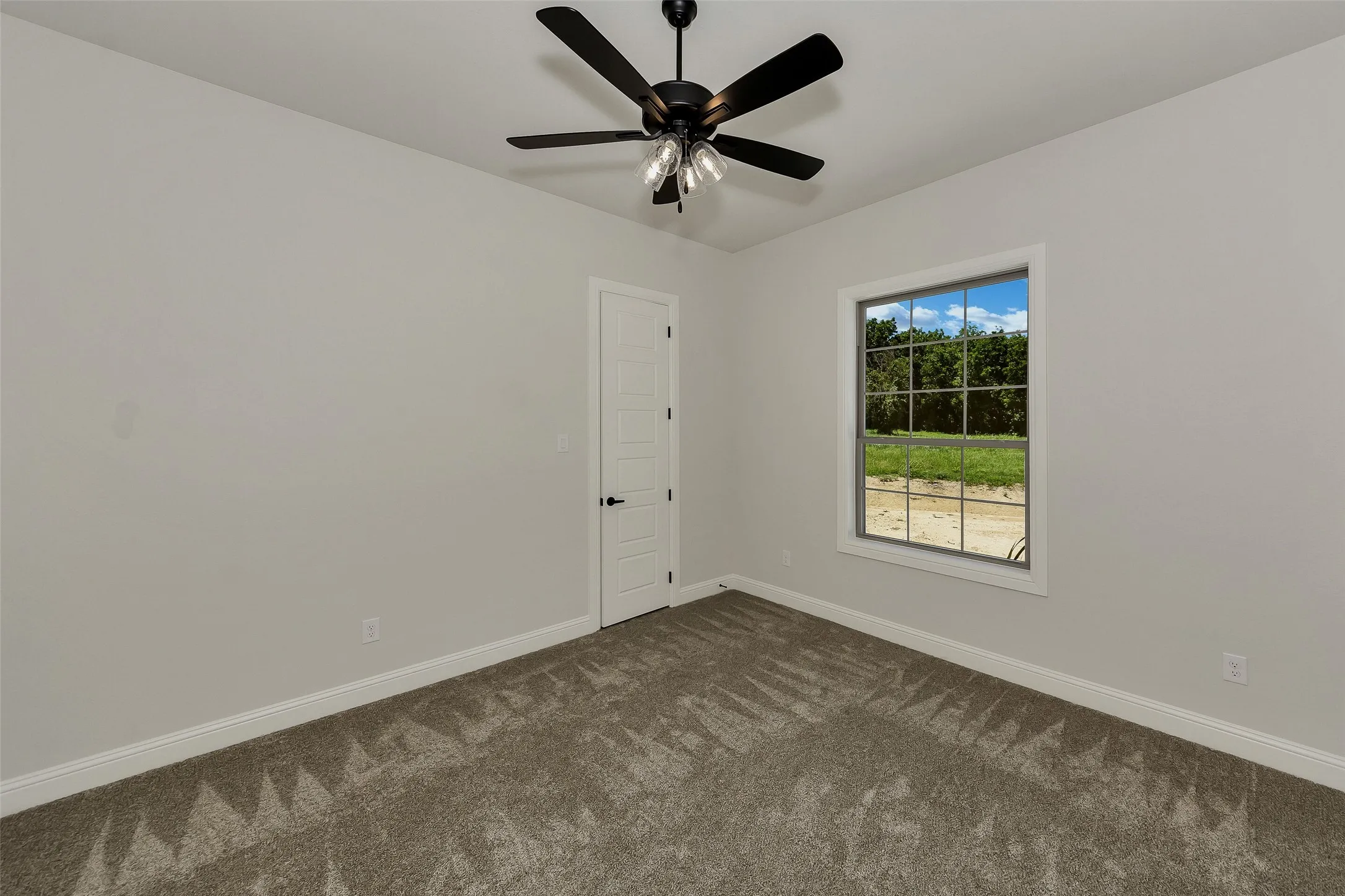Empty room featuring dark carpet and ceiling fan