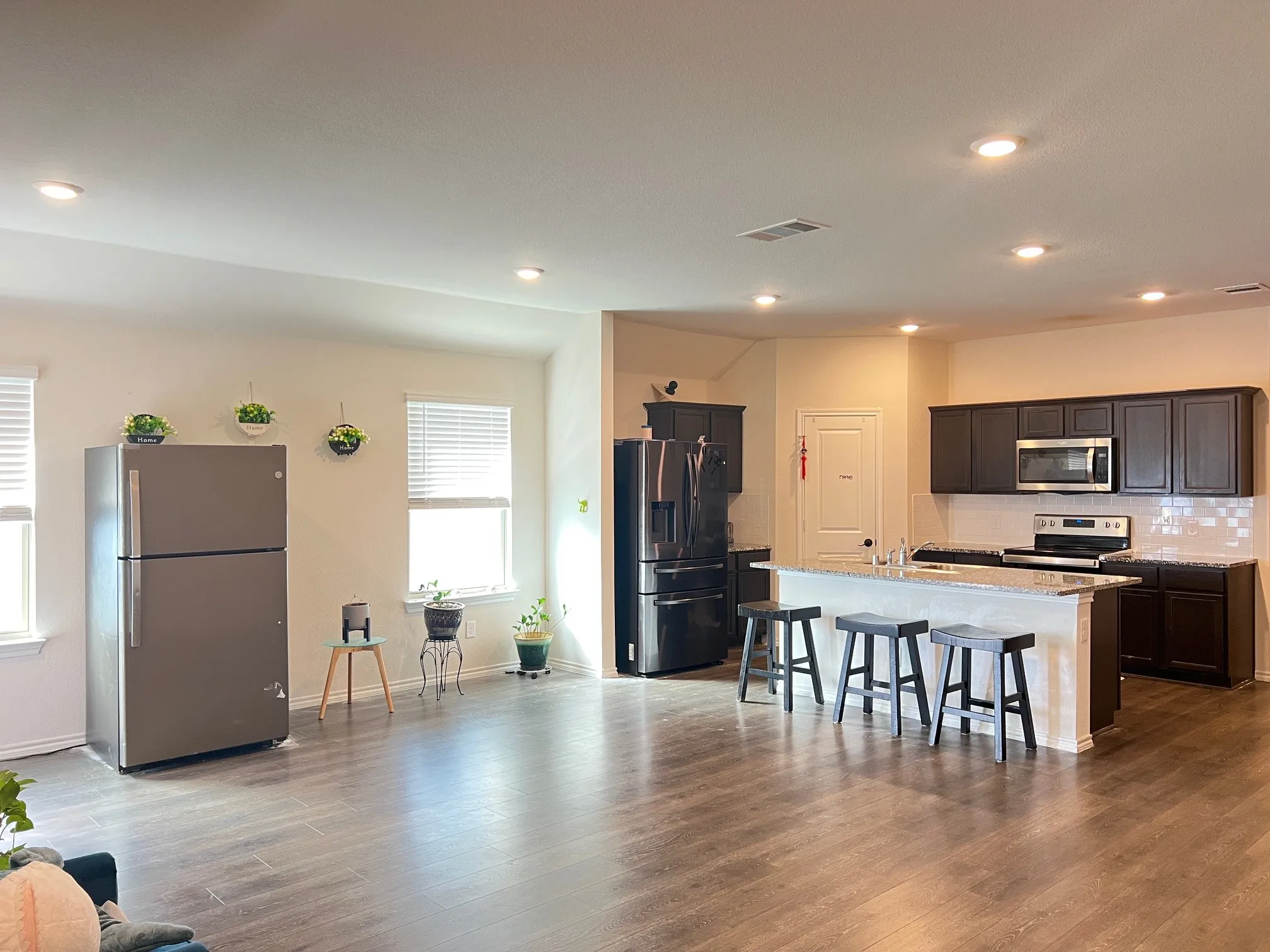 Kitchen with appliances with stainless steel finishes, backsplash, a kitchen breakfast bar, a kitchen island with sink, and wood finished floors