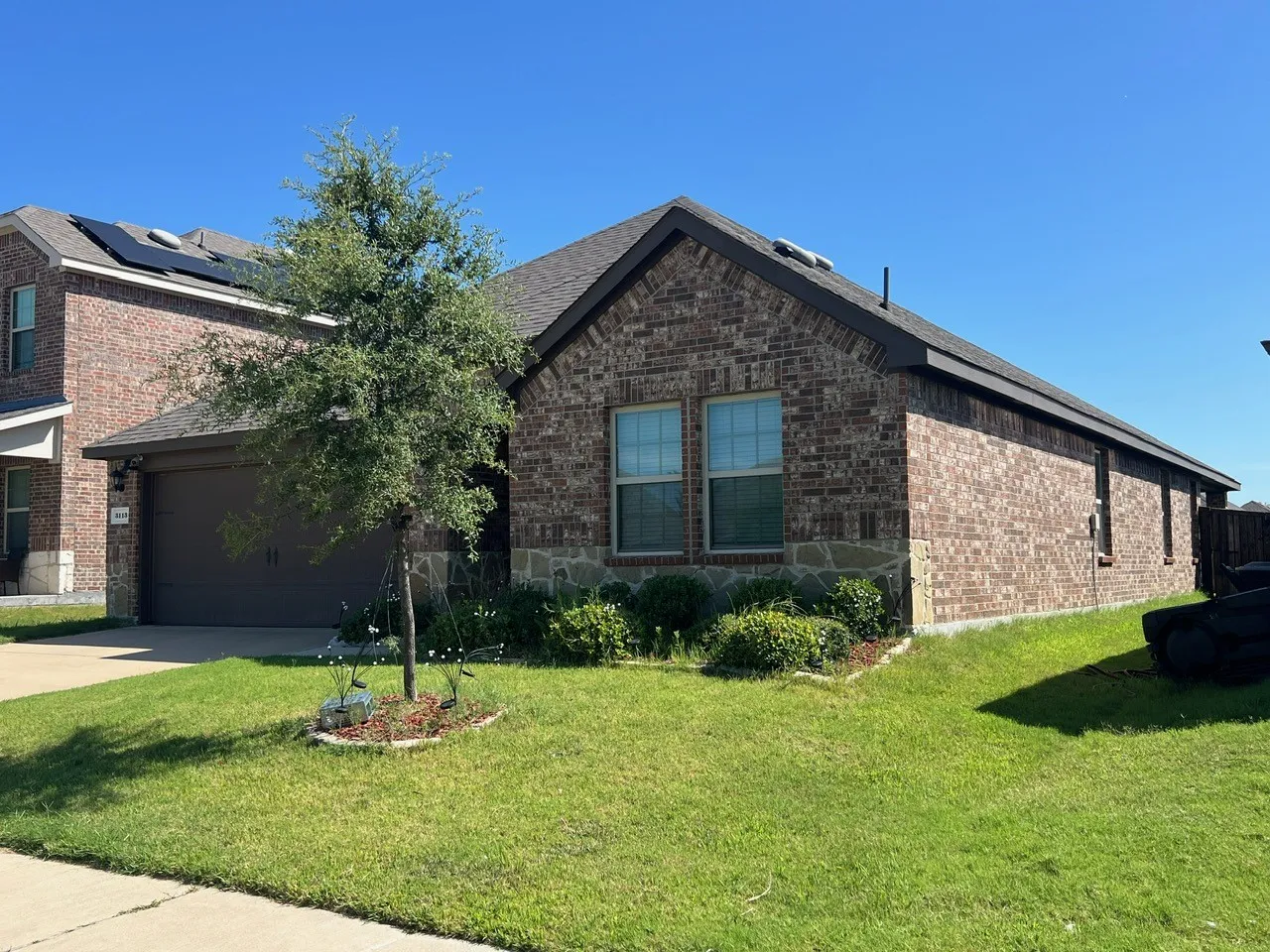 View of front of home featuring brick siding, concrete driveway, a front yard, an attached garage, and roof with shingles