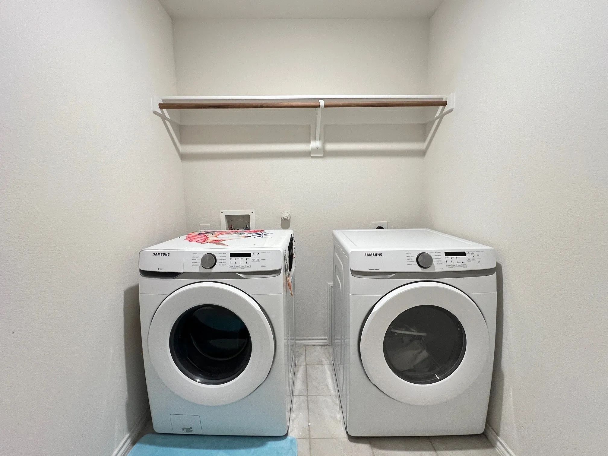 Washroom with washing machine and dryer and light tile patterned flooring