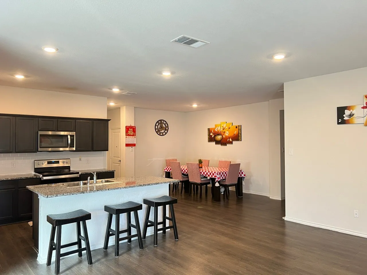 Kitchen with appliances with stainless steel finishes, backsplash, a kitchen bar, a kitchen island with sink, and light stone countertops
