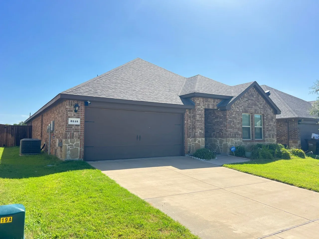 View of front of property with brick siding, an attached garage, roof with shingles, and concrete driveway