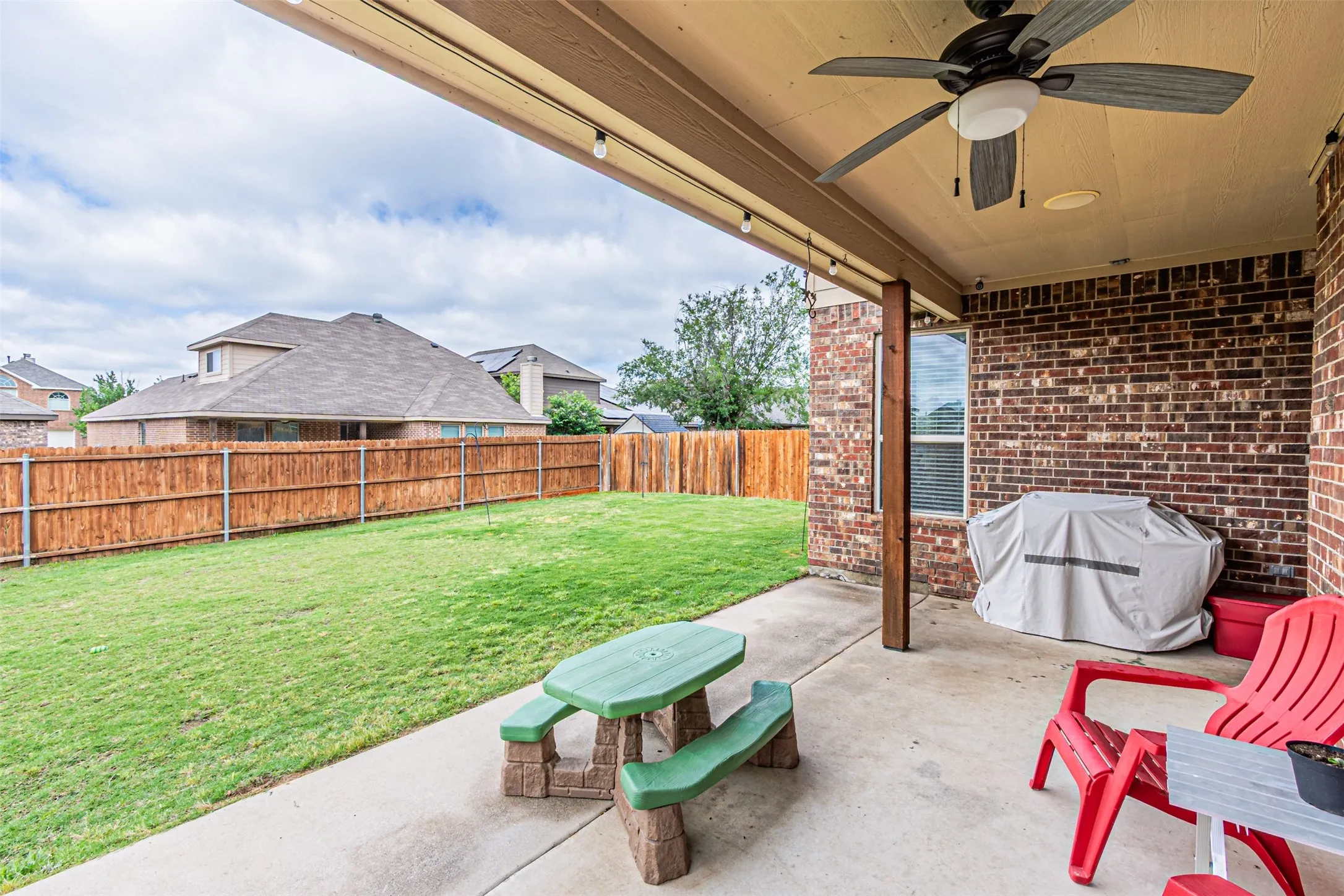 Fenced backyard with a ceiling fan and a patio area