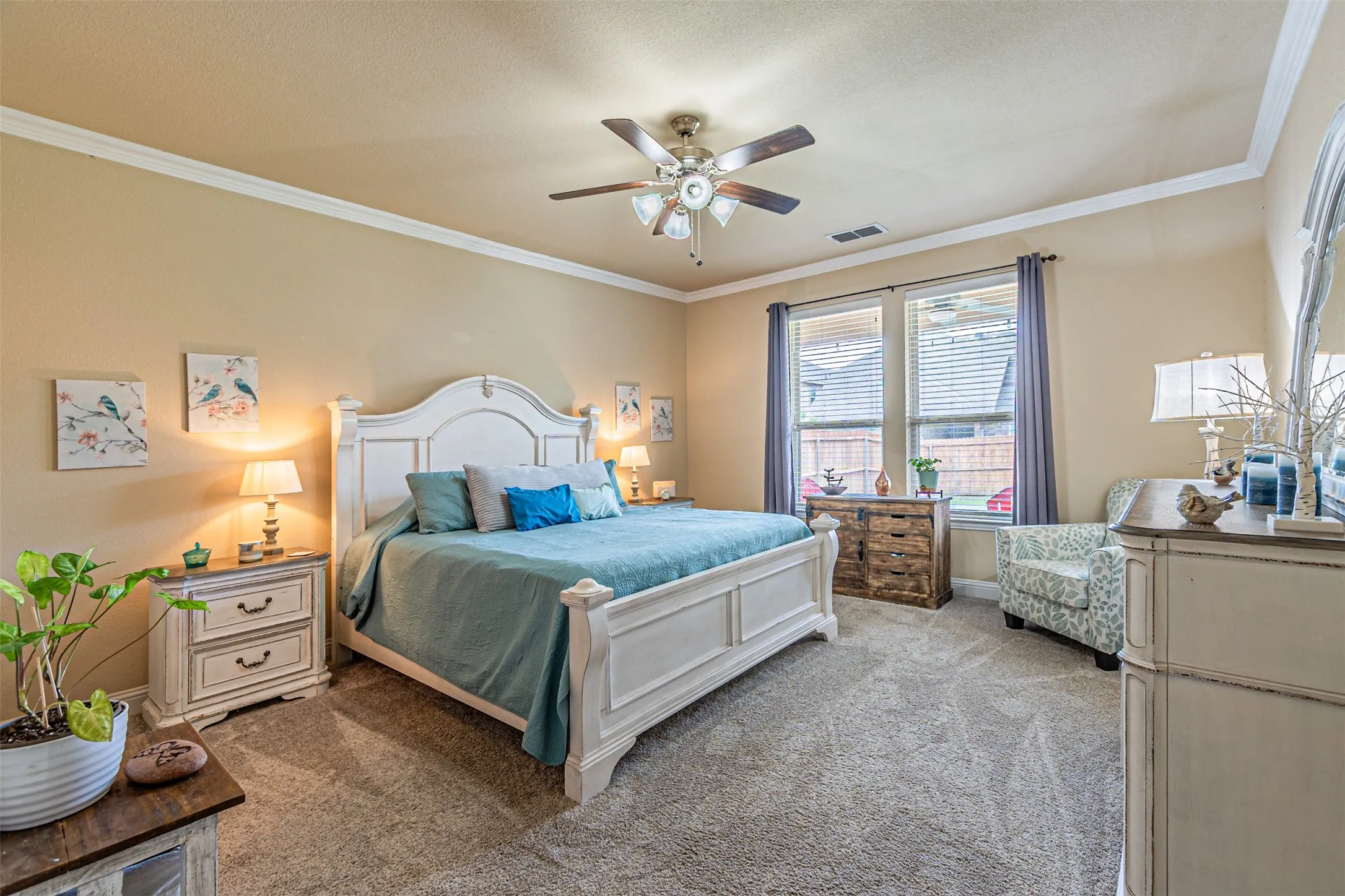 Bedroom with light colored carpet, ornamental molding, a ceiling fan, and a textured ceiling