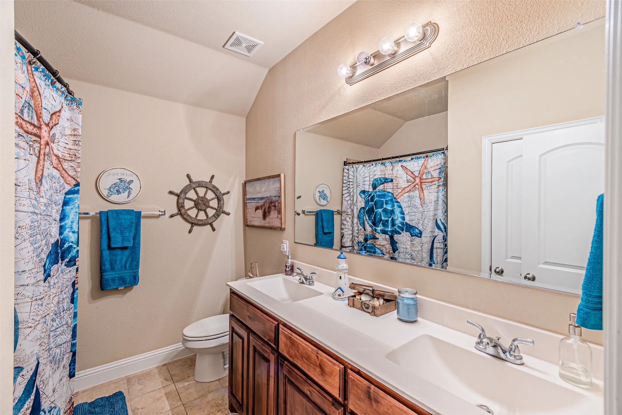Bathroom with double vanity, tile patterned flooring, and curtained shower