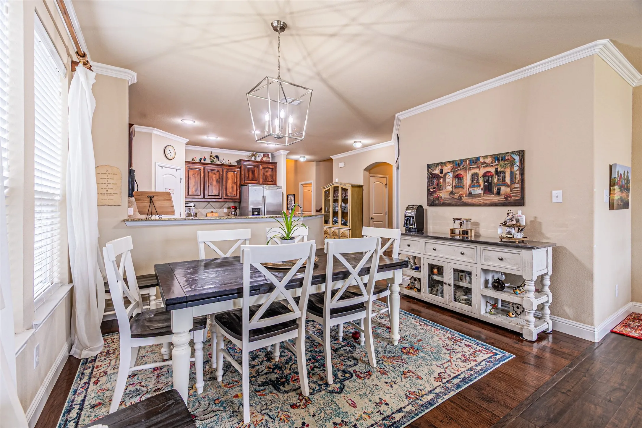 Dining area featuring arched walkways, plenty of natural light, a chandelier, crown molding, and dark wood finished floors