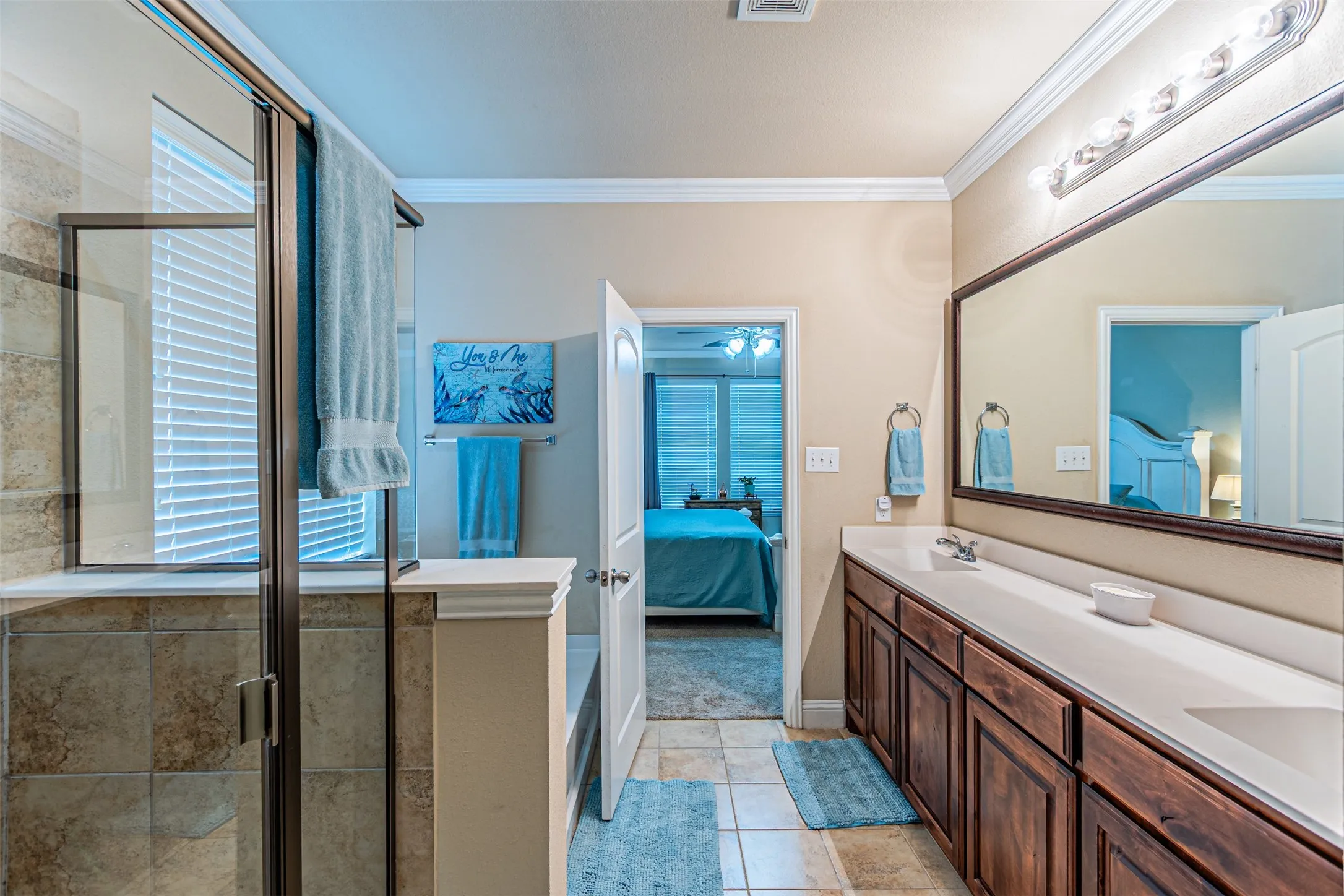 Ensuite bathroom with crown molding, double vanity, a shower stall, and tile patterned floors
