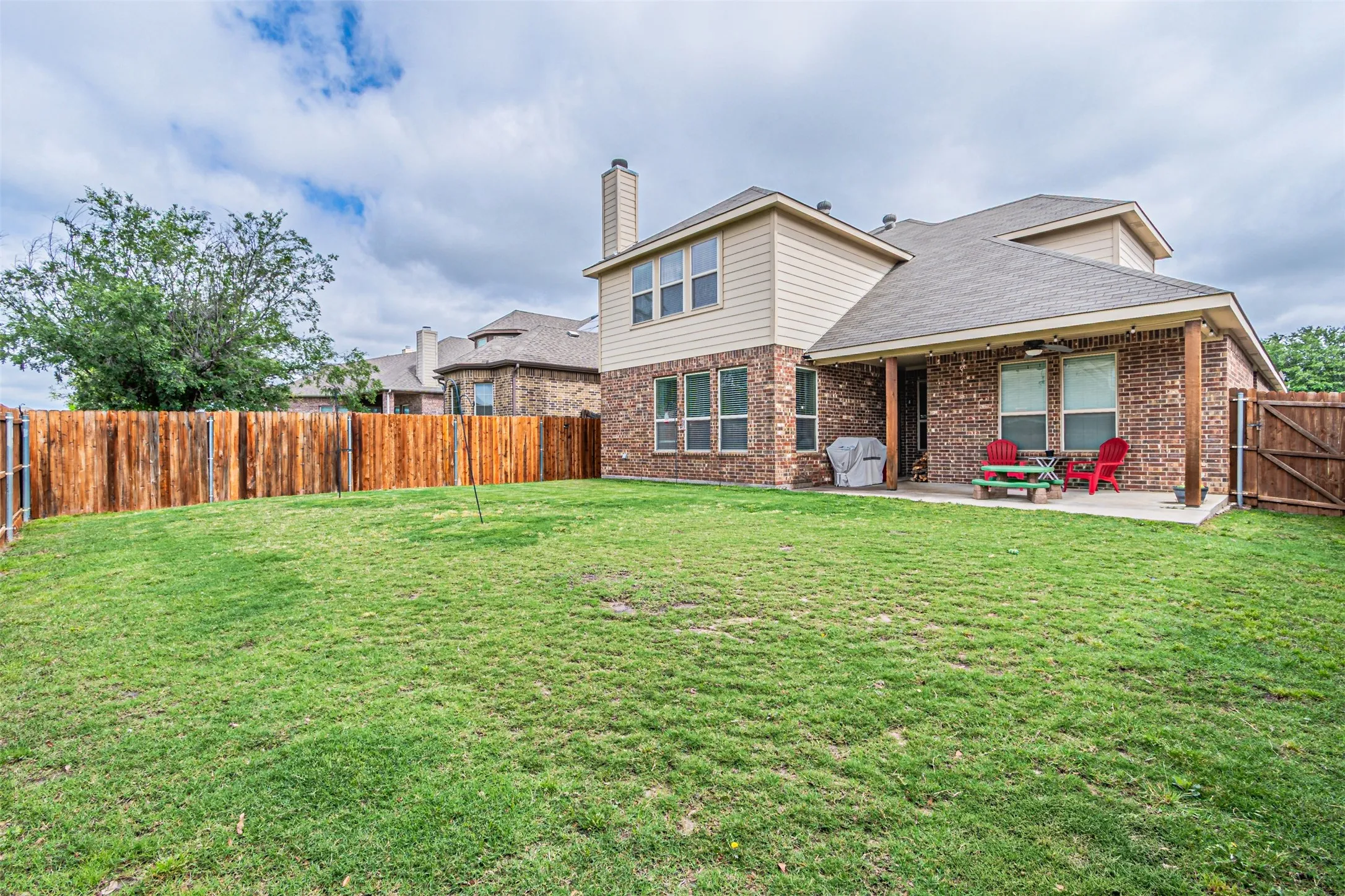 Back of house featuring a patio area, a fenced backyard, brick siding, roof with shingles, and a chimney