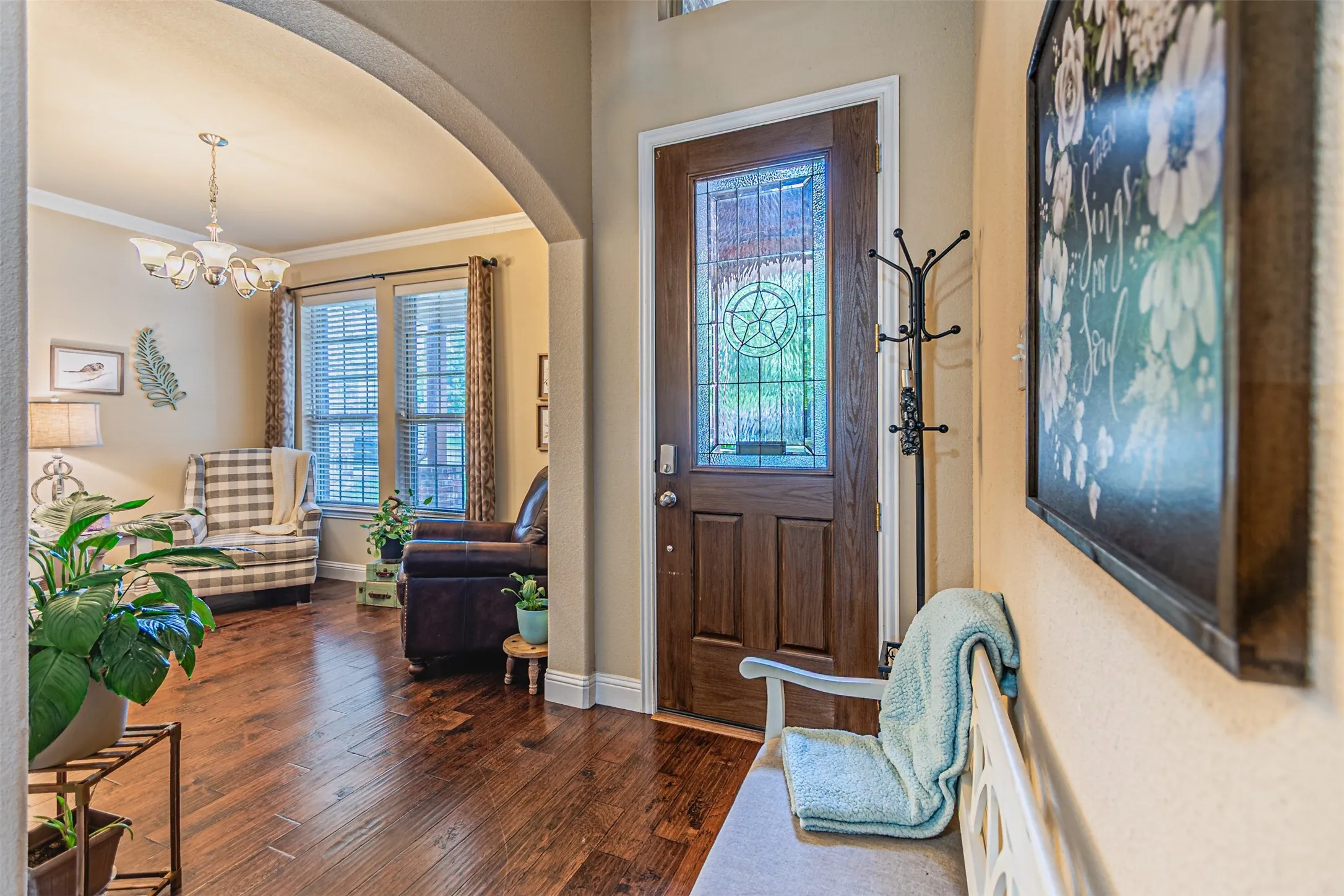 Entrance foyer with dark wood-style flooring, arched walkways, ornamental molding, and a chandelier