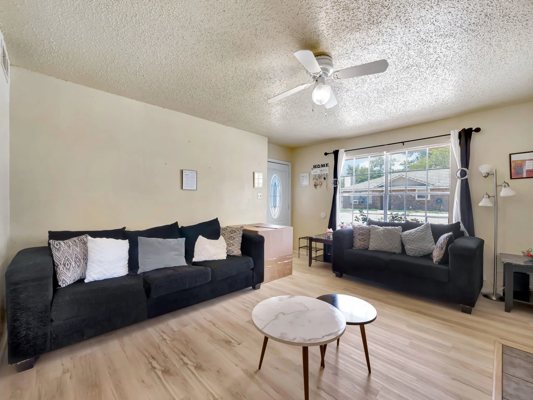 Living area featuring a textured ceiling, light wood-type flooring, and ceiling fan