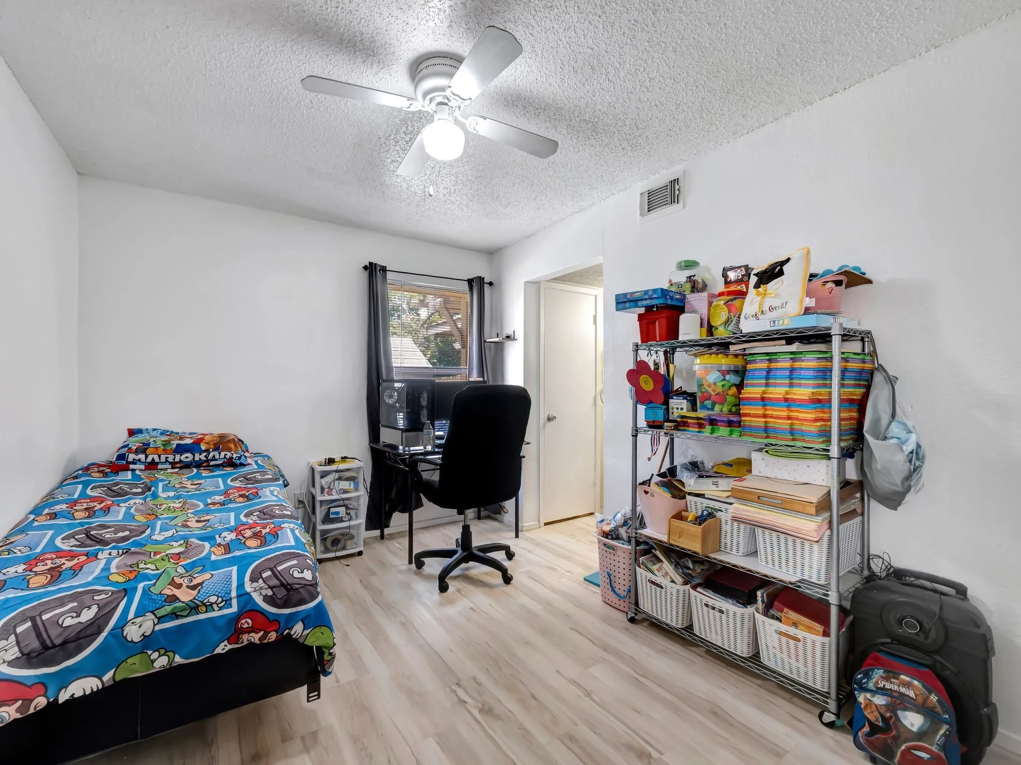 Bedroom featuring a textured ceiling, light wood-type flooring, ceiling fan, and an office area