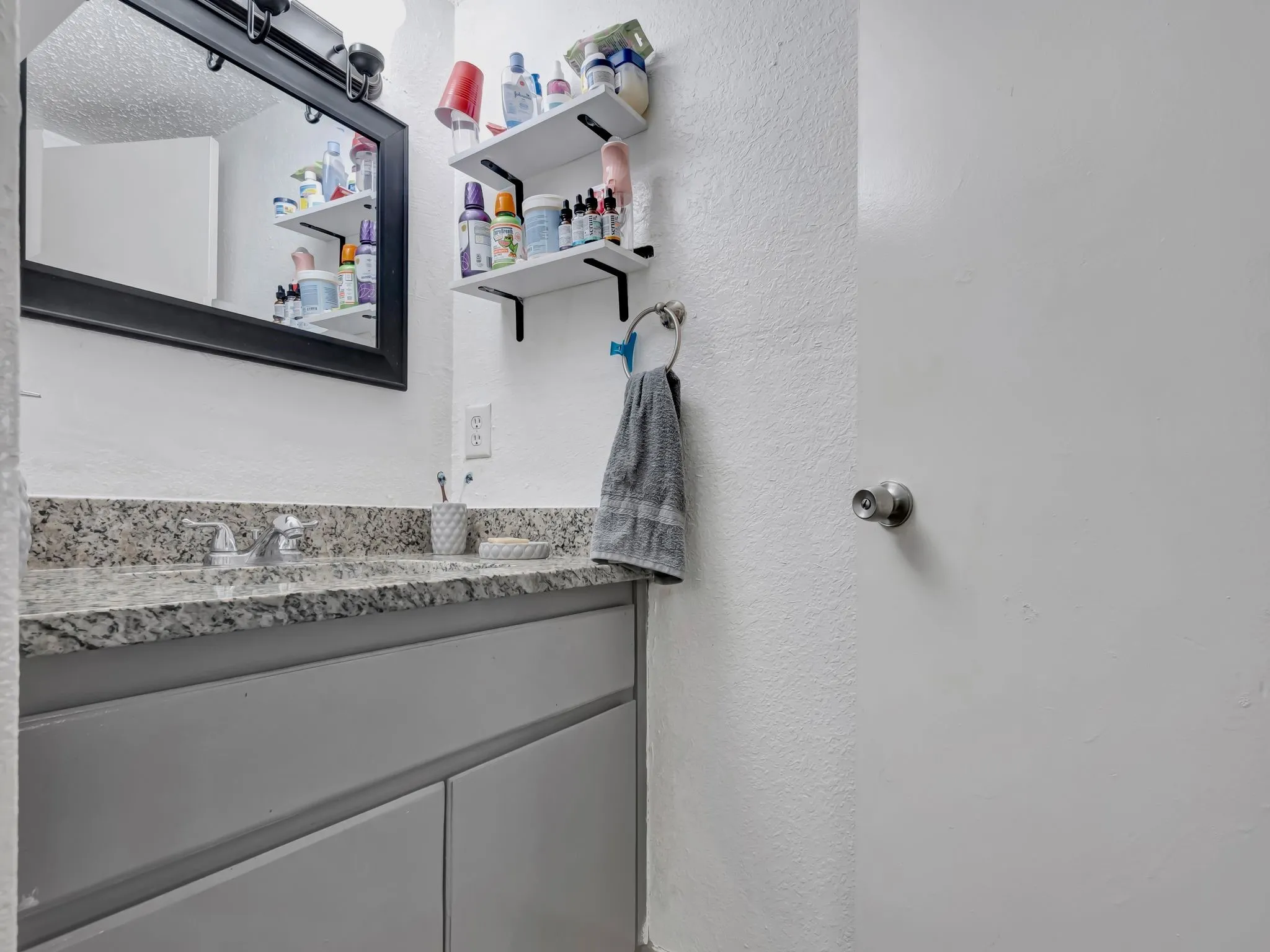 Bathroom with a textured wall and vanity