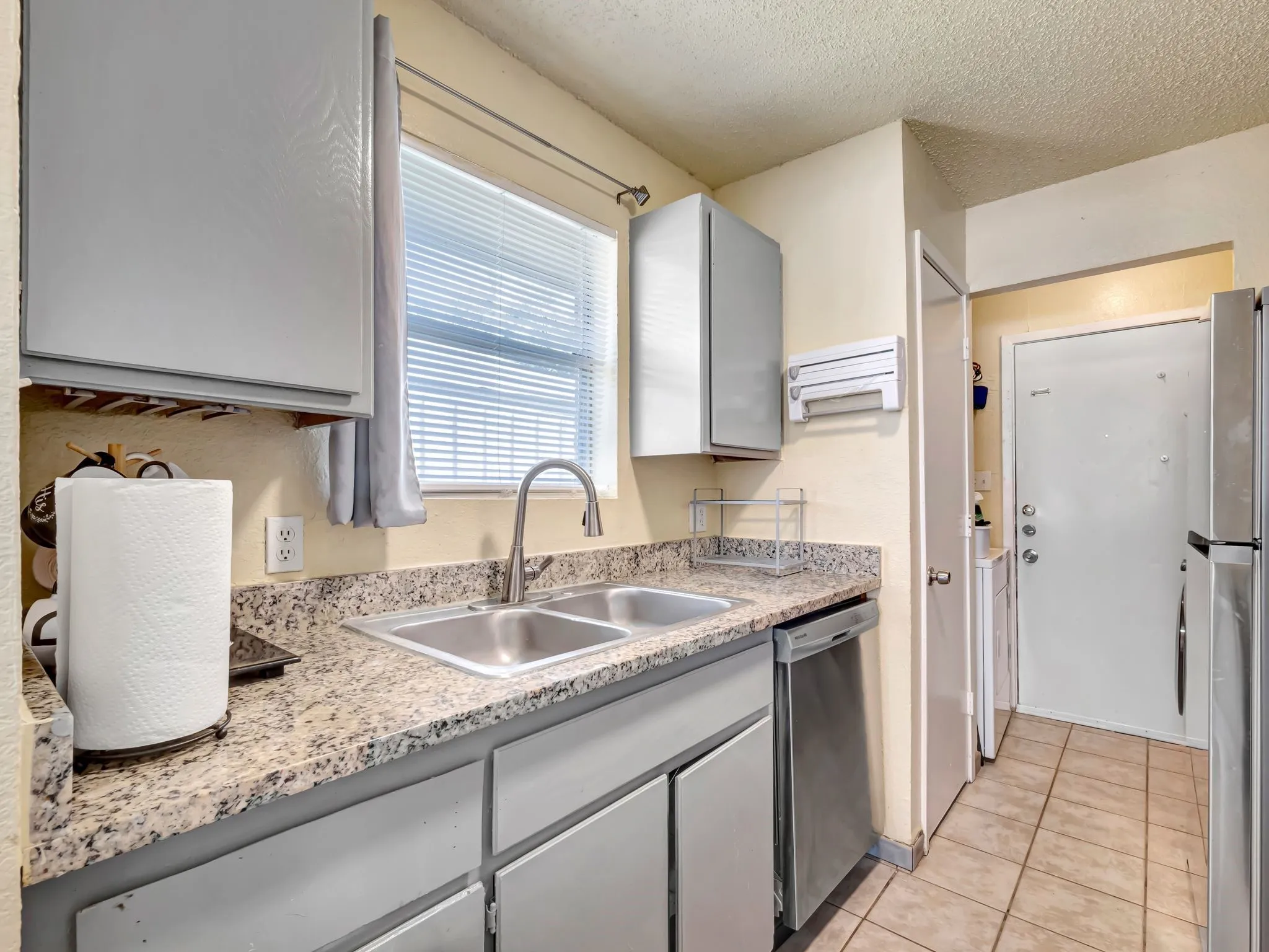 Kitchen featuring a textured ceiling, gray cabinets, stainless steel appliances, light countertops, and light tile patterned floors