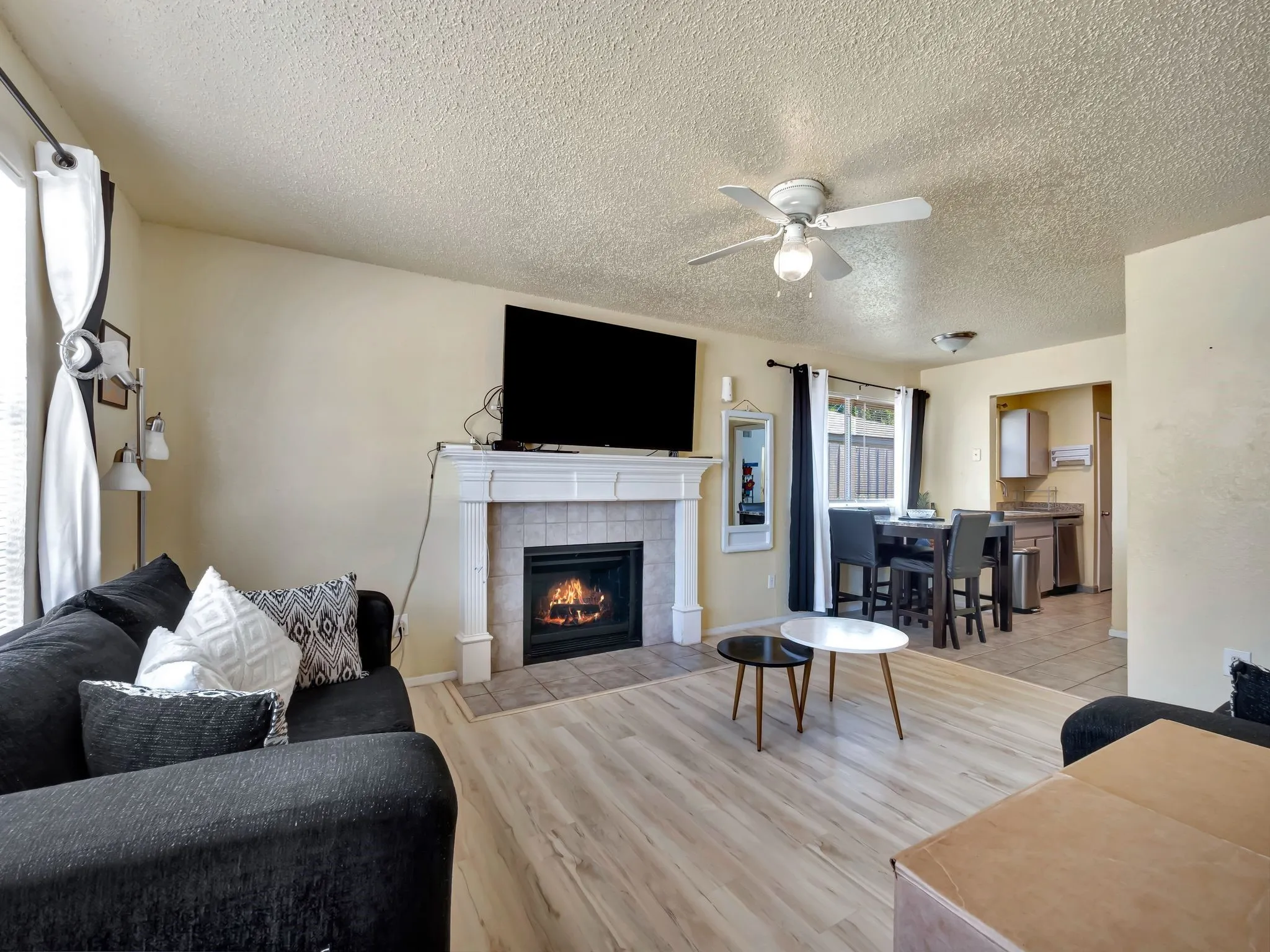 Living room featuring a textured ceiling, a ceiling fan, light wood-style flooring, and a fireplace
