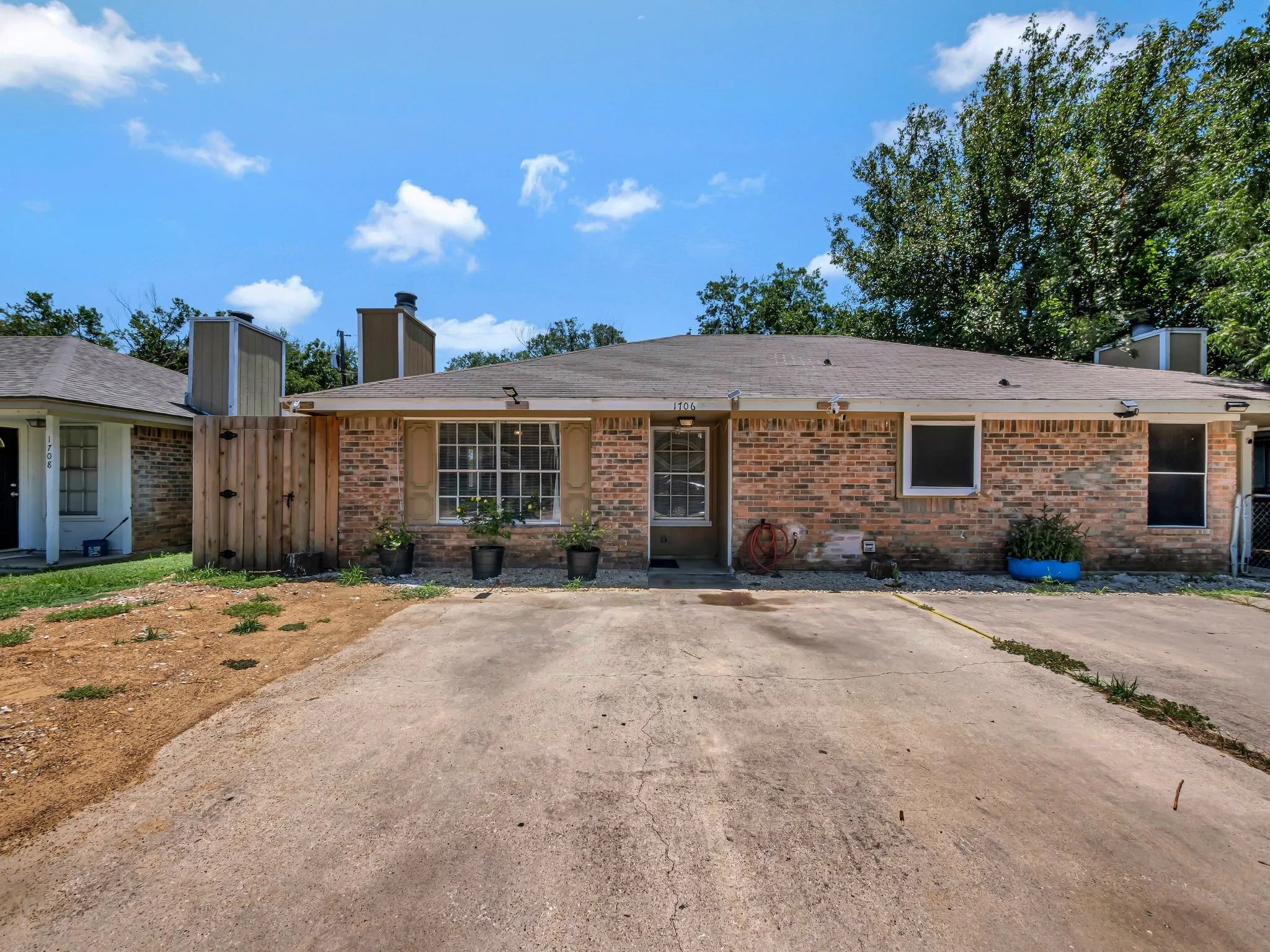 Ranch-style home with a chimney, brick siding, and a gate