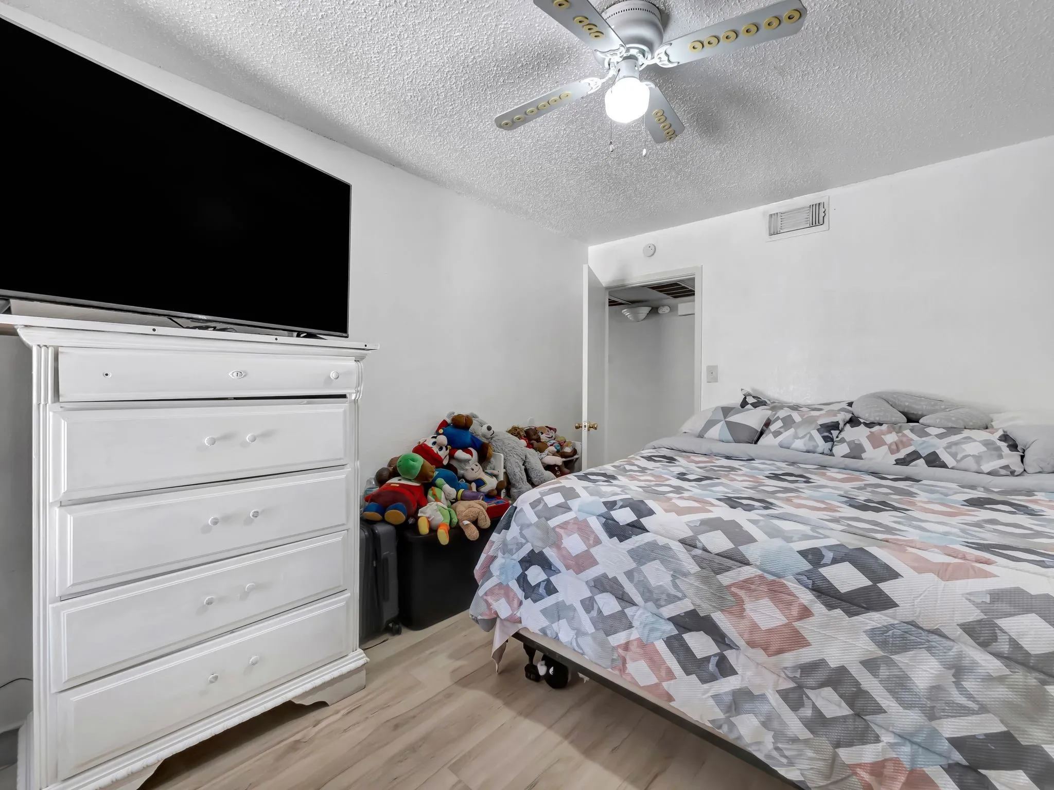 Bedroom with light wood-type flooring, a textured ceiling, and a ceiling fan