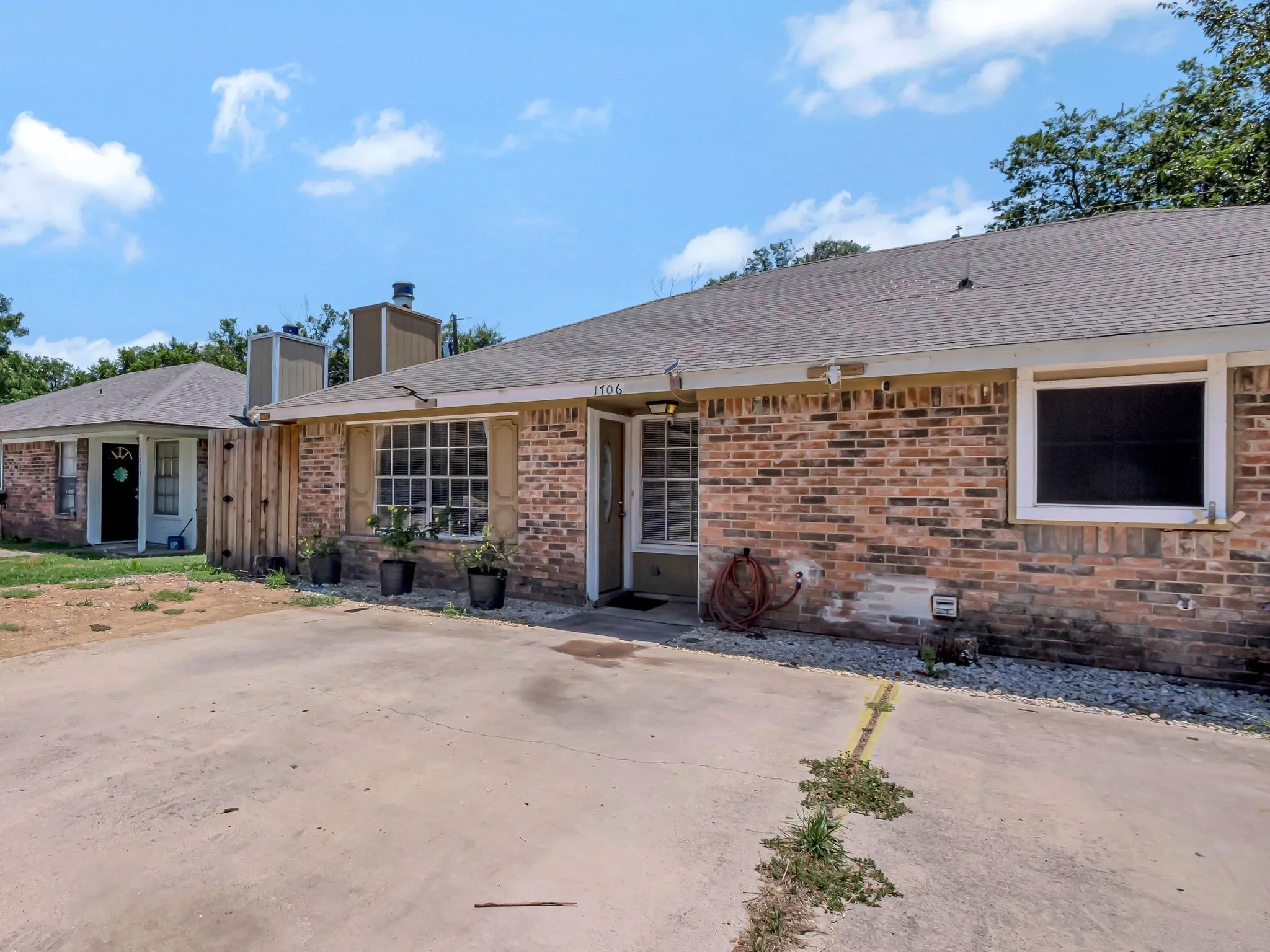 View of front of property with brick siding, a chimney, a shingled roof, and a patio