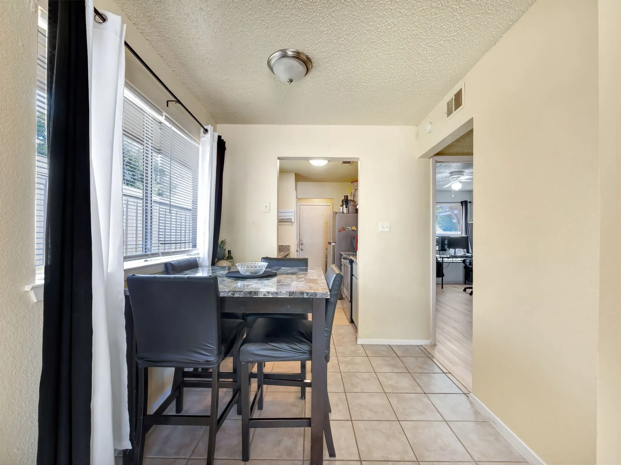 Dining space featuring healthy amount of natural light, light tile patterned floors, and a textured ceiling