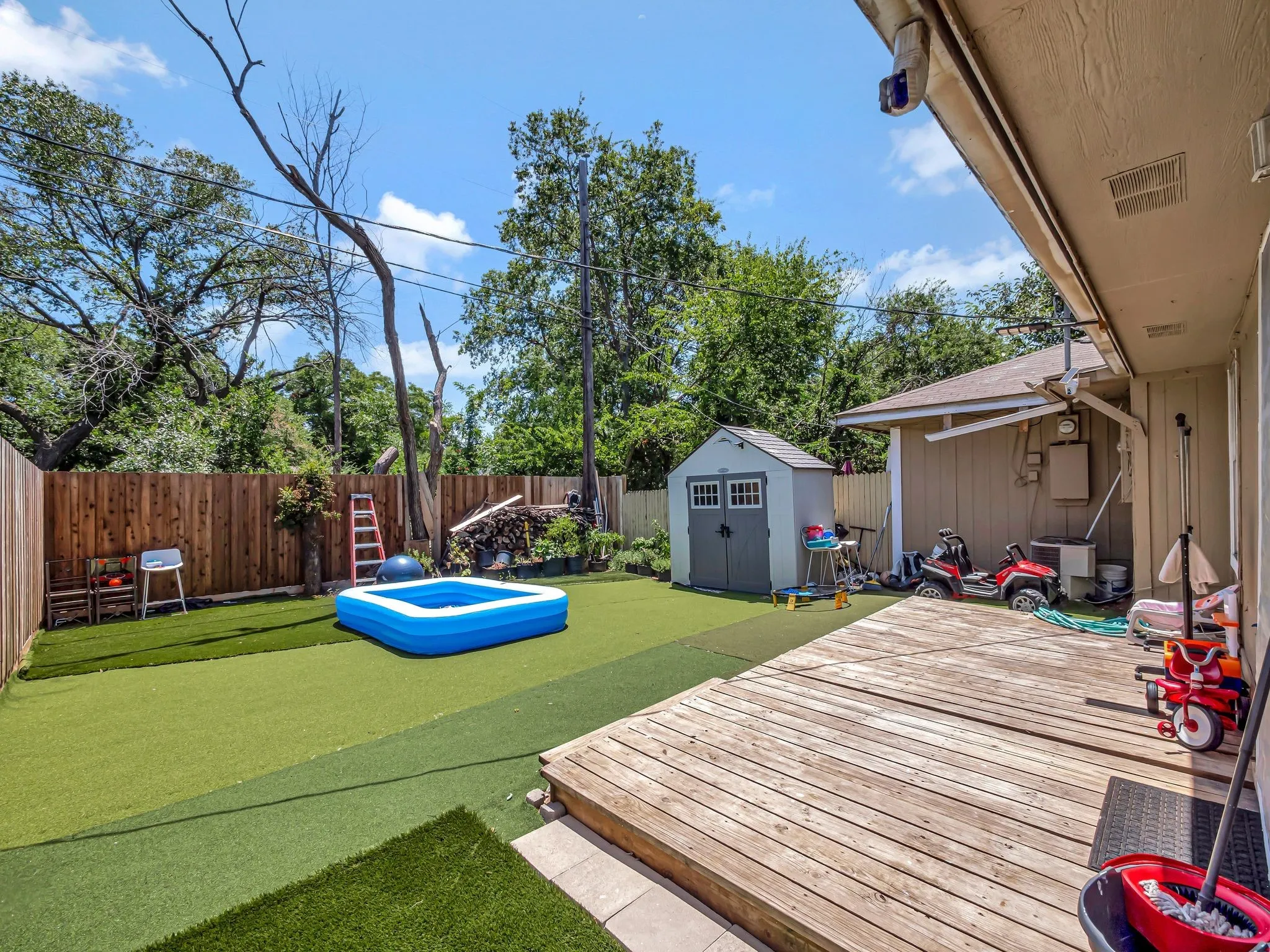 Wooden terrace with a fenced backyard and a storage unit