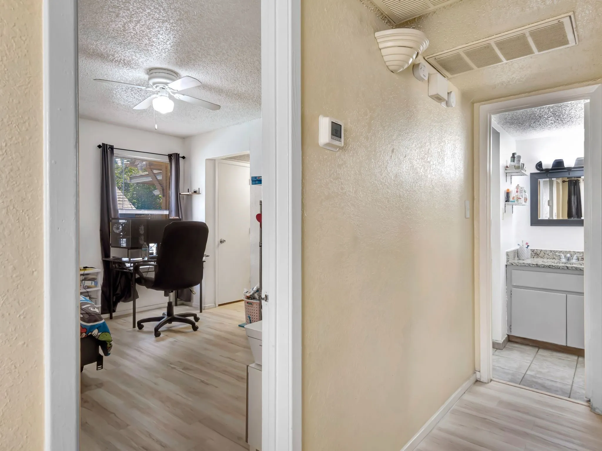 Office space featuring a textured ceiling, a textured wall, light wood-style flooring, and ceiling fan