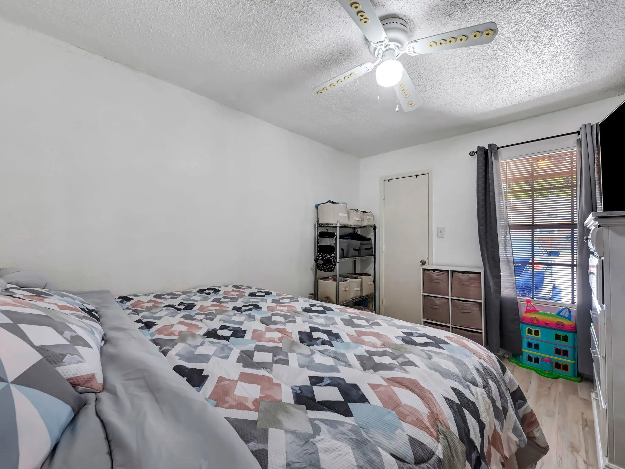Bedroom with a textured ceiling, light wood-style floors, and ceiling fan
