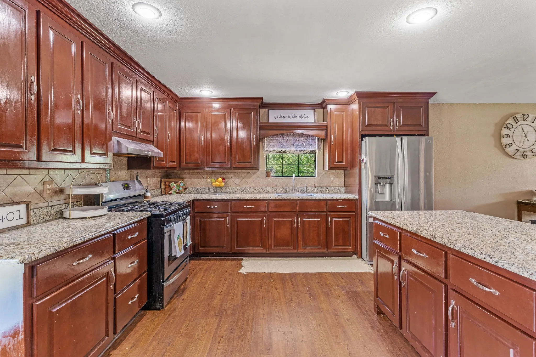 Kitchen featuring stainless steel appliances, light wood-style floors, recessed lighting, backsplash, and under cabinet range hood