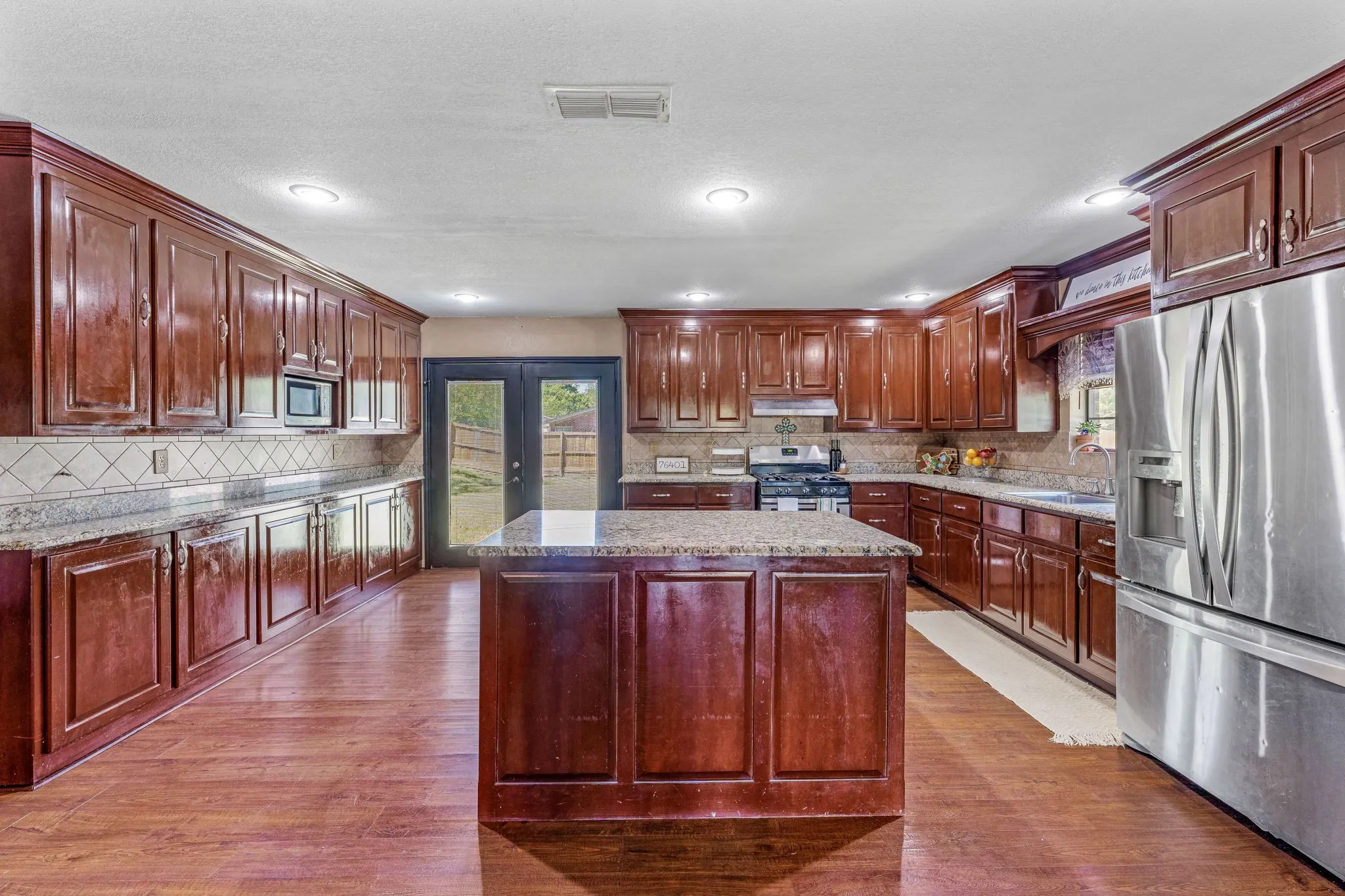 Kitchen with stainless steel appliances, french doors, wood finished floors, healthy amount of natural light, and recessed lighting
