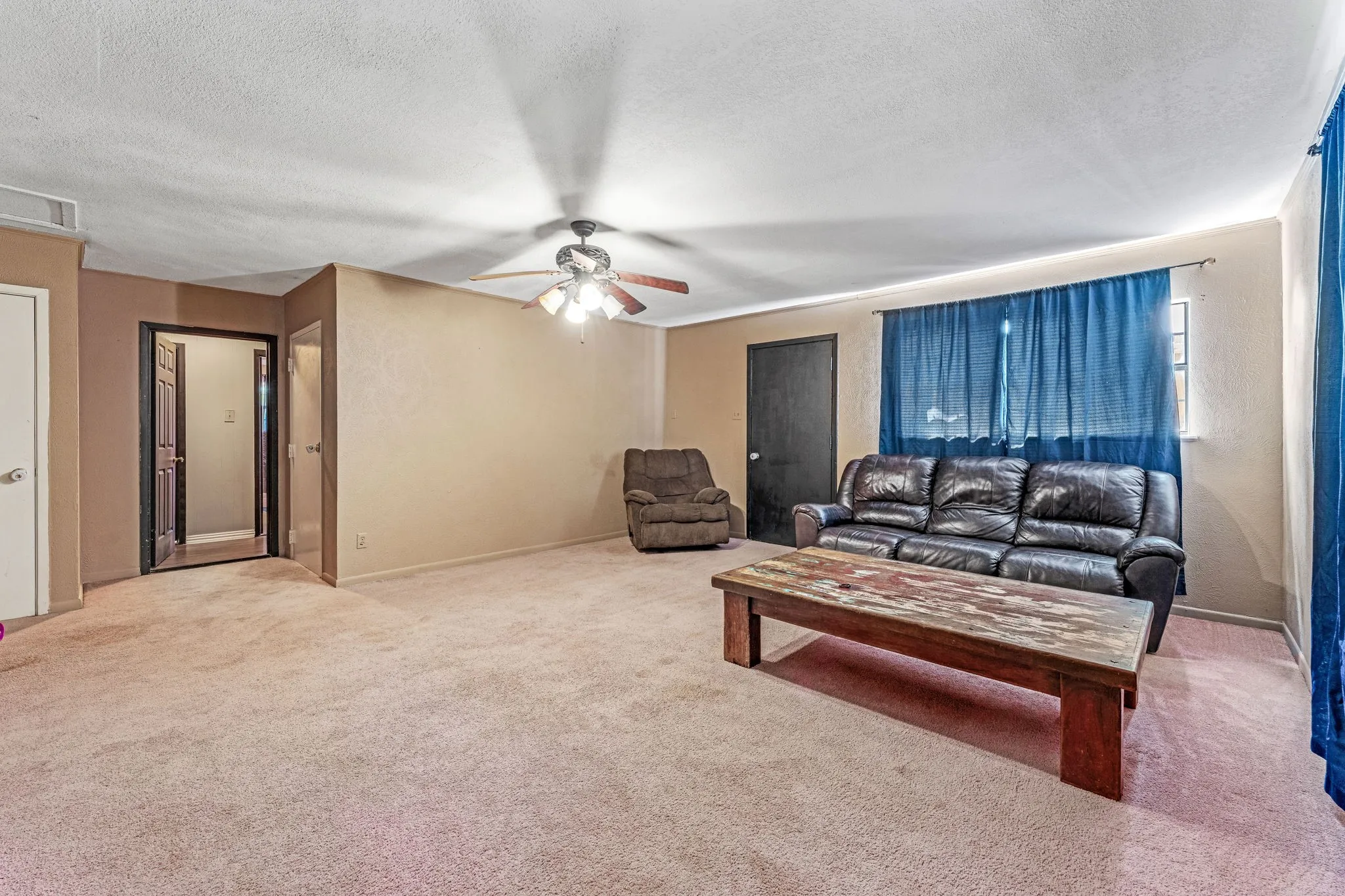 Carpeted living area with a textured ceiling and ceiling fan